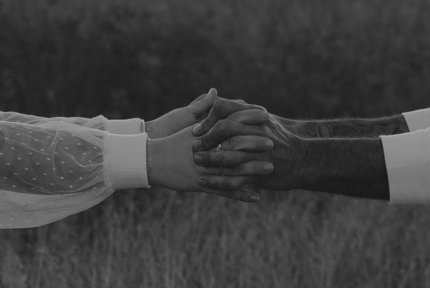 Two hands reach across a table to shake hands in a black and white photograph.
