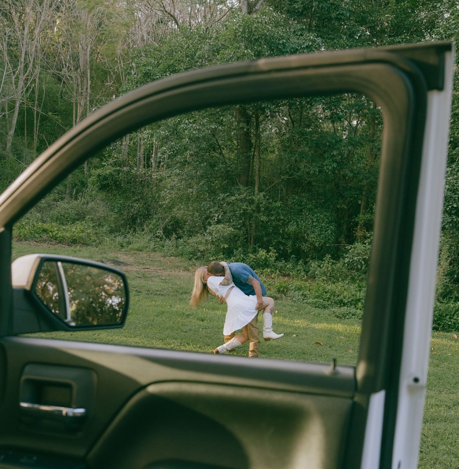 Person looking through car window during outdoor journey through wooded area in natural lighting.