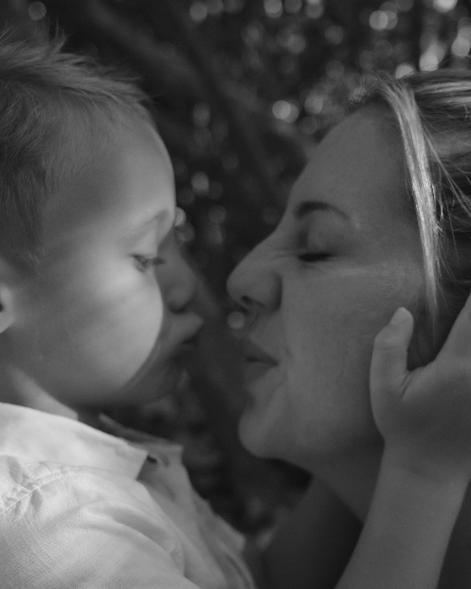 A tender black and white photograph captures a loving moment between parent and child in soft focus.