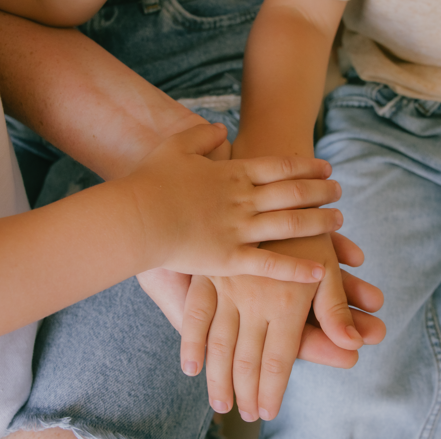 Close-up view of small hands gently overlapping on a gray surface.