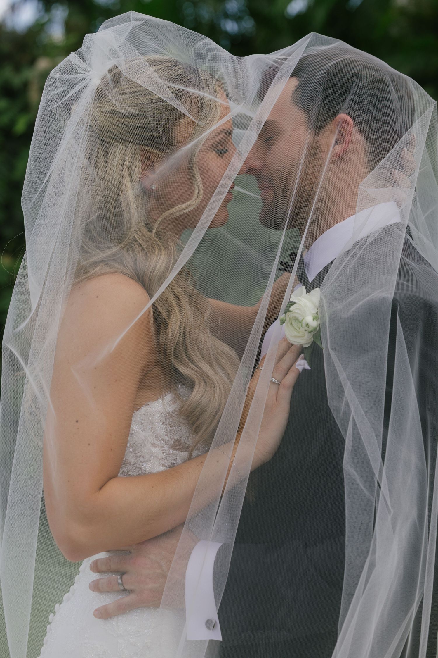 A romantic wedding sequence shows a couple sharing intimate kisses under a flowing white veil outdoors.