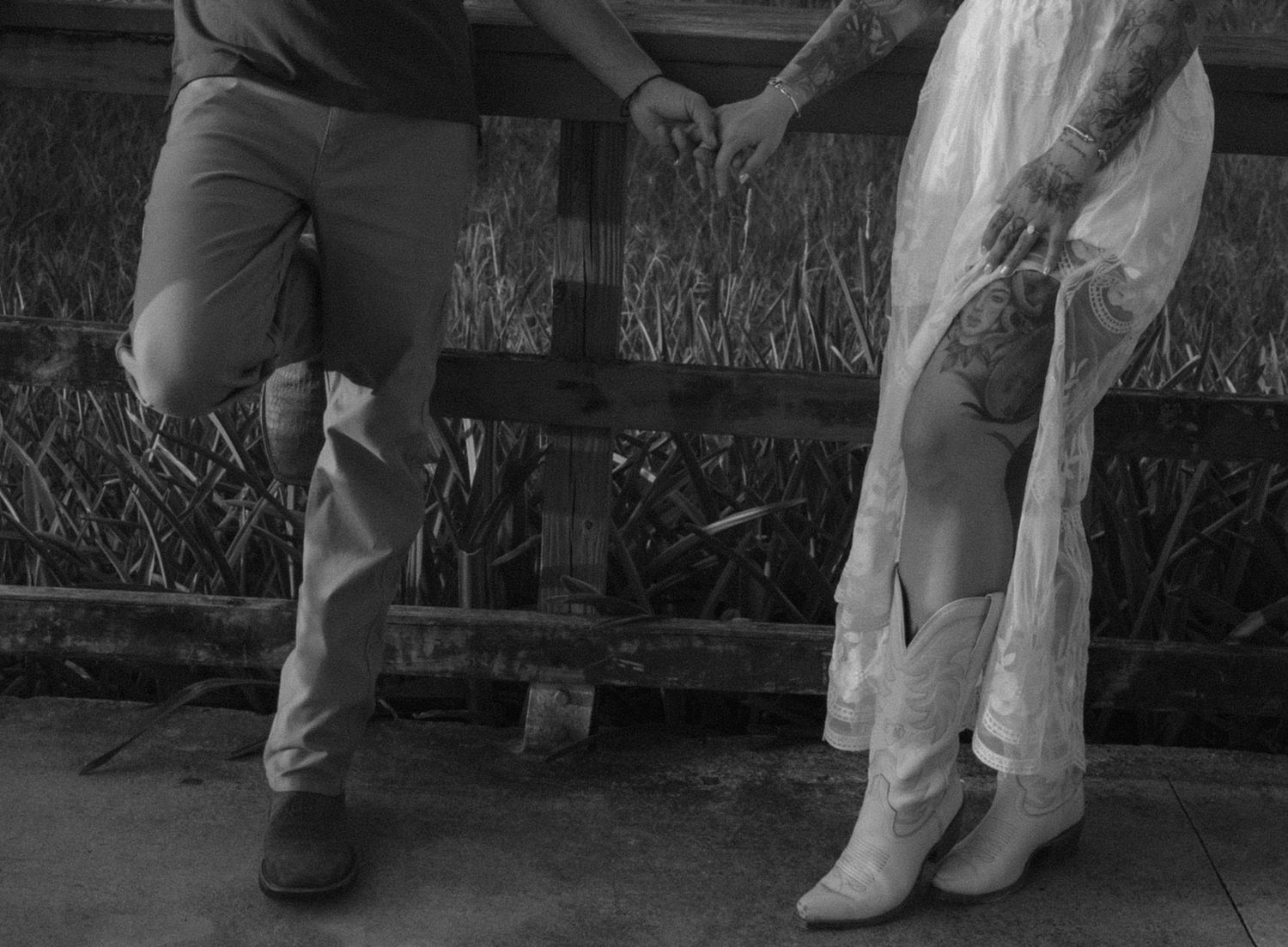 Close-up shot of boots and casual wear against a wooden railing backdrop.
