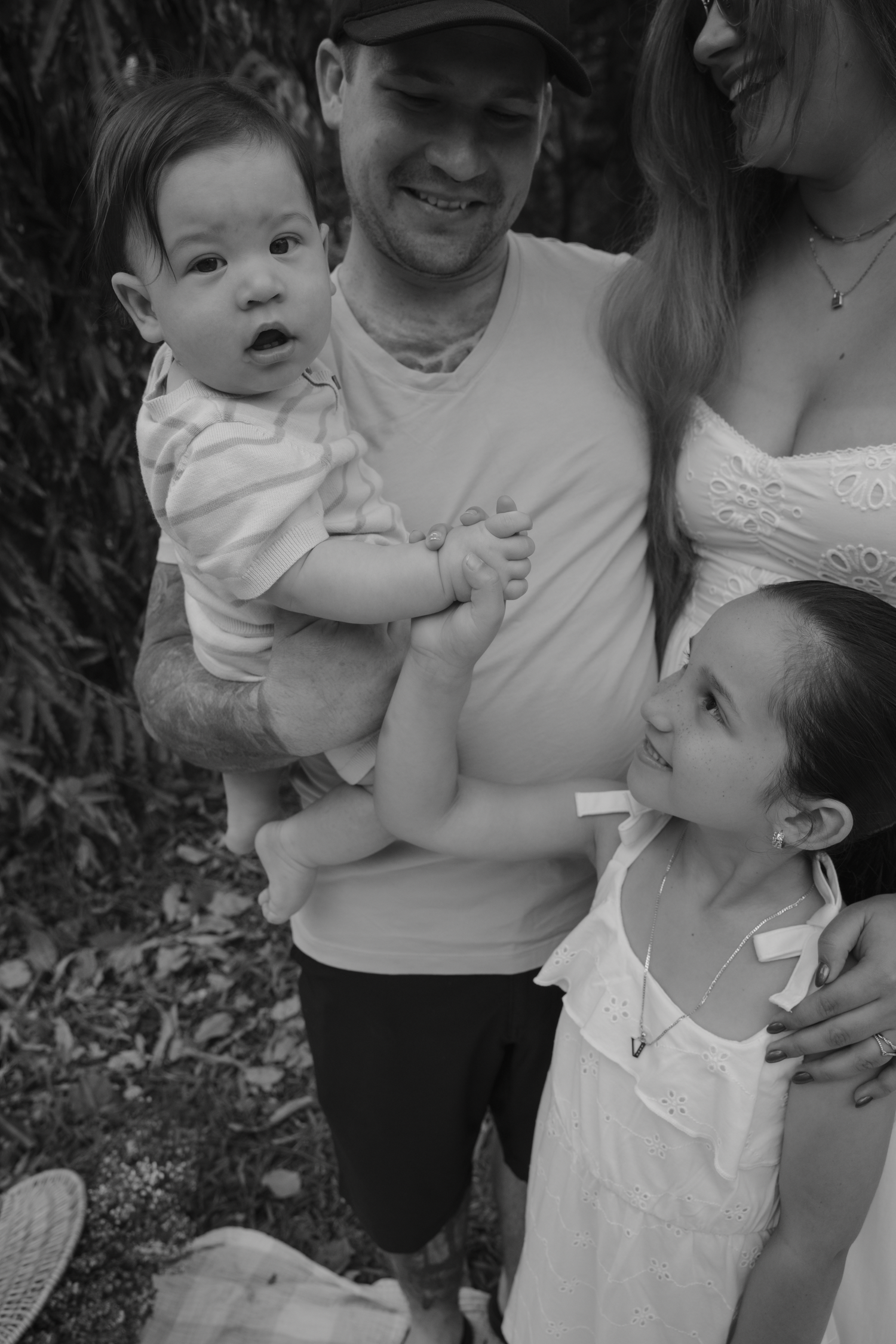 Black and white family photoshoot showing tender moments in a garden setting.