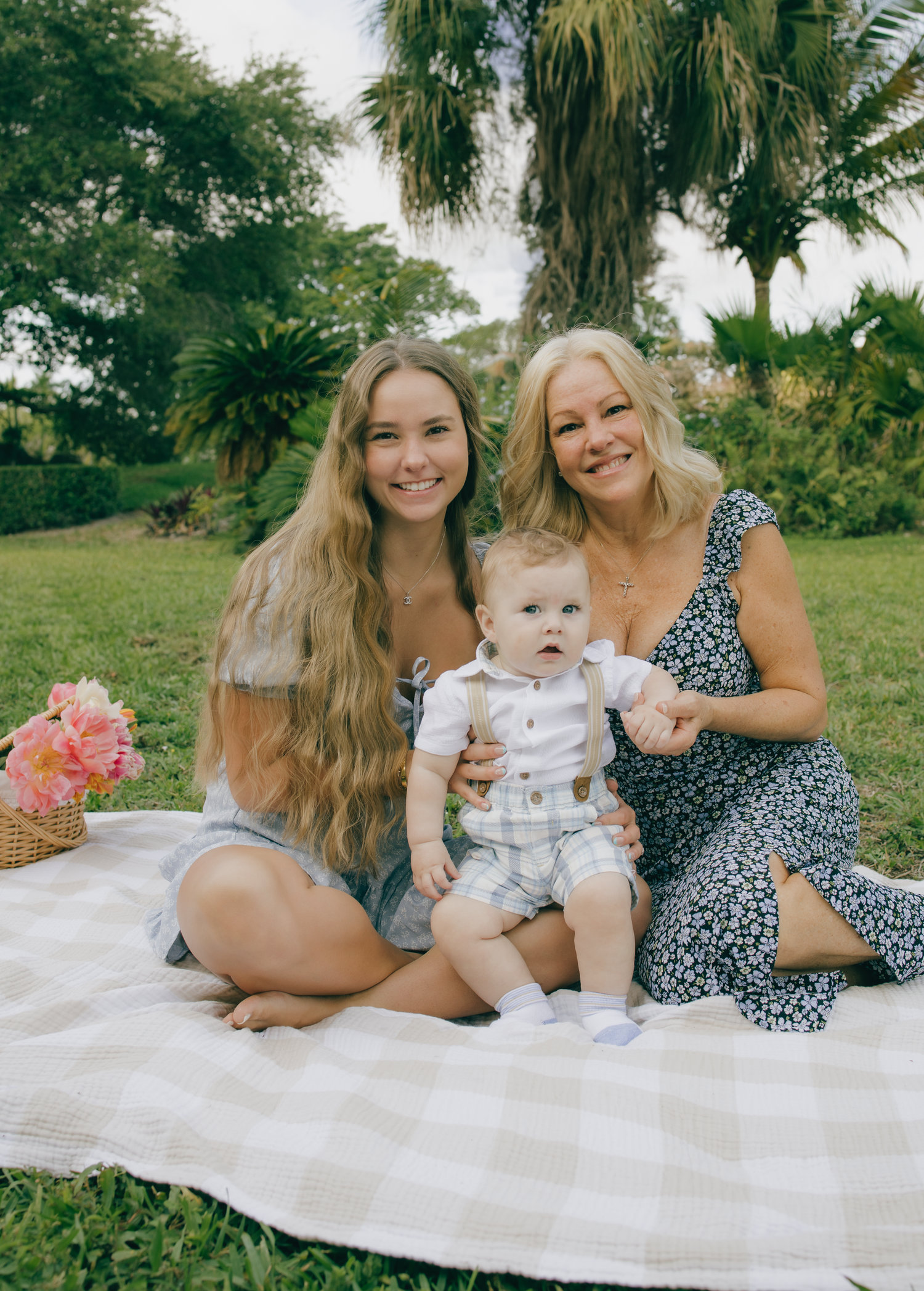 Summer picnic scene with family relaxing on white blanket under palm trees.