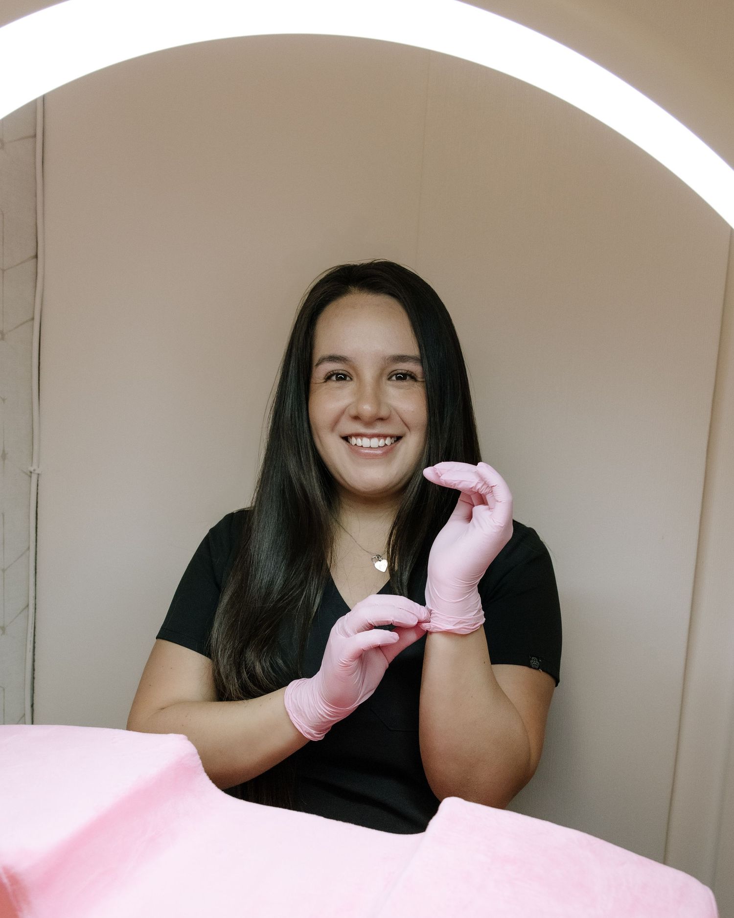 A beautician wearing pink gloves prepares for a beauty treatment.