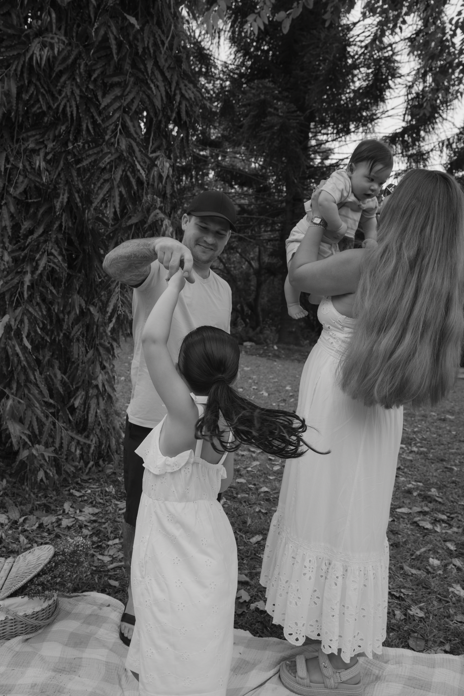 A series of black and white photos showing two people in white dresses dancing together in a garden setting.