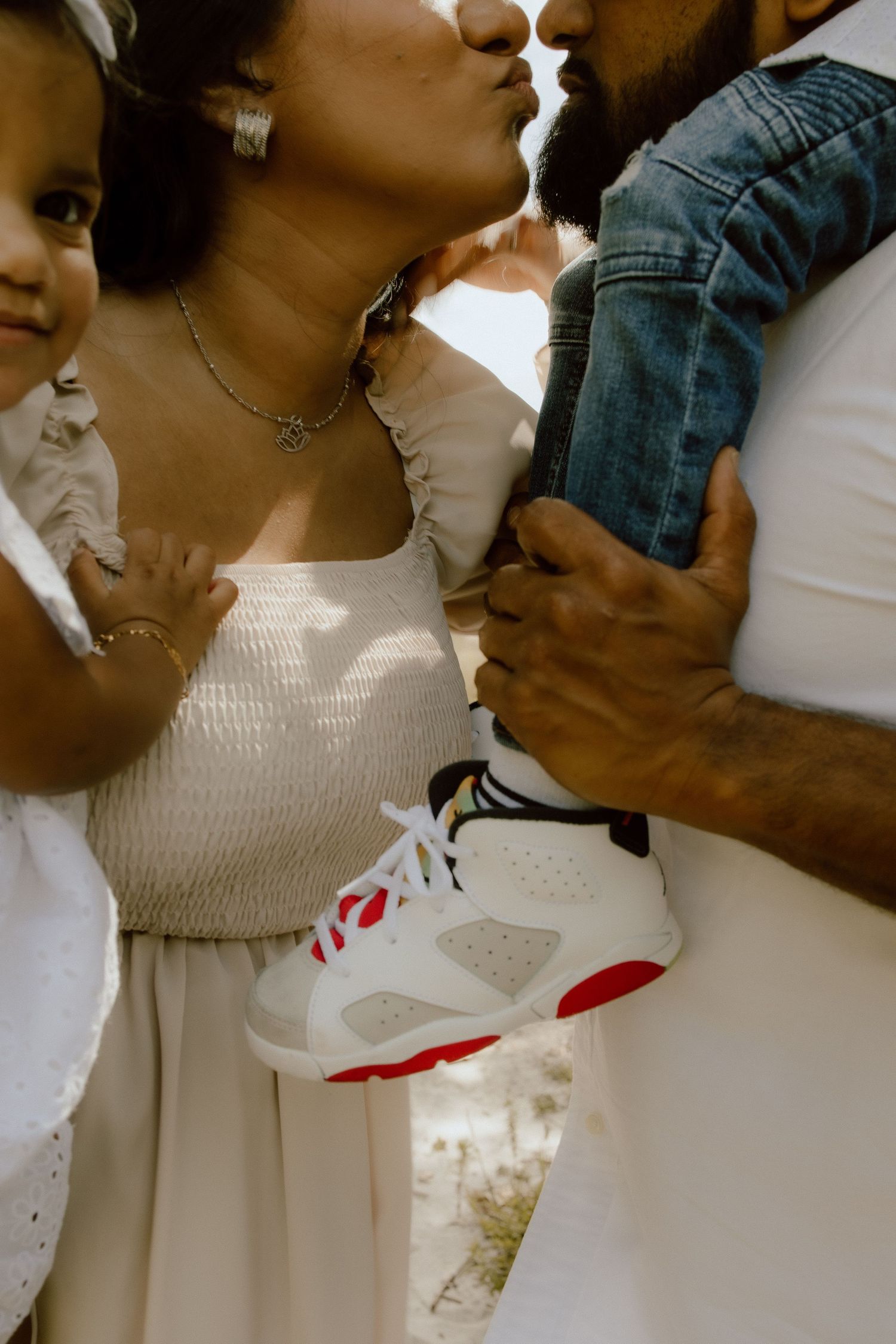 A close-up view of someone in a white dress holding a baby, shown in a sequence of four connected photos.