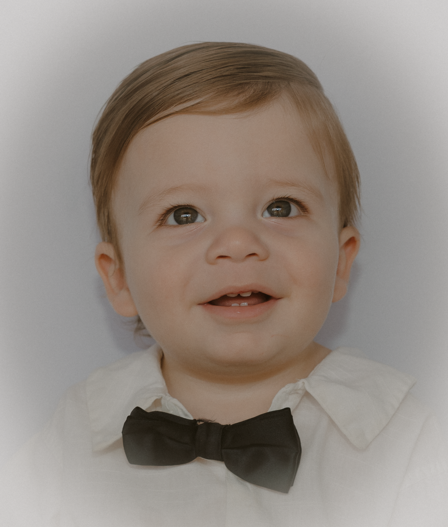 Four close-up portraits of a baby wearing a black bowtie against a white background.