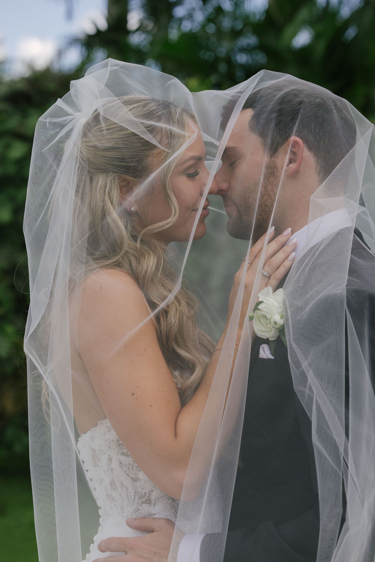 A romantic wedding photo series showing a couple sharing a kiss under a flowing white veil.
