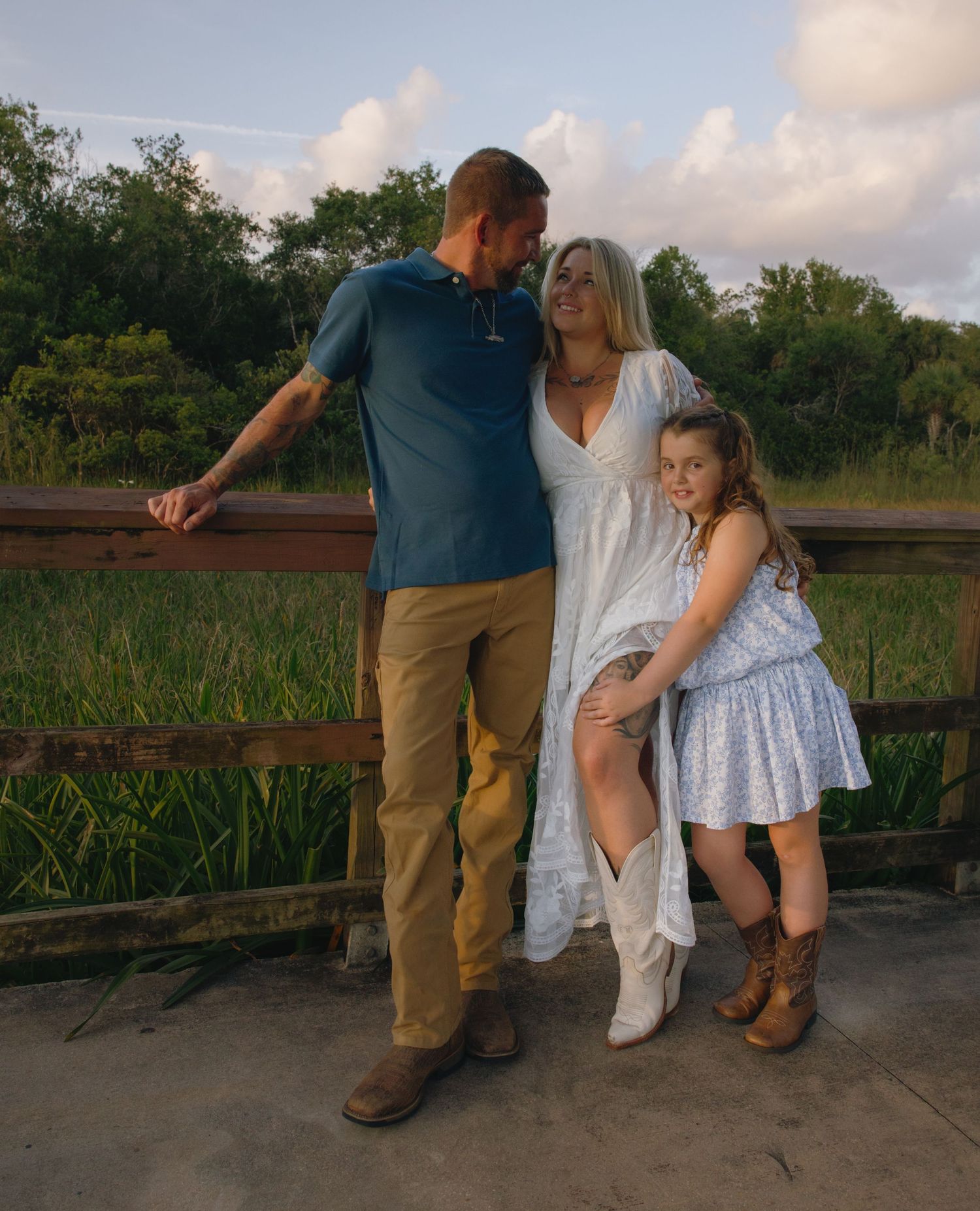 A family poses together on a wooden boardwalk with marsh grass in the background.