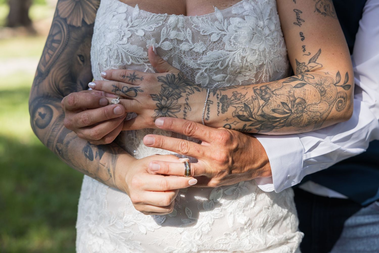 Close up of heavily tattooed arms and hands with wedding rings during a ceremony.
