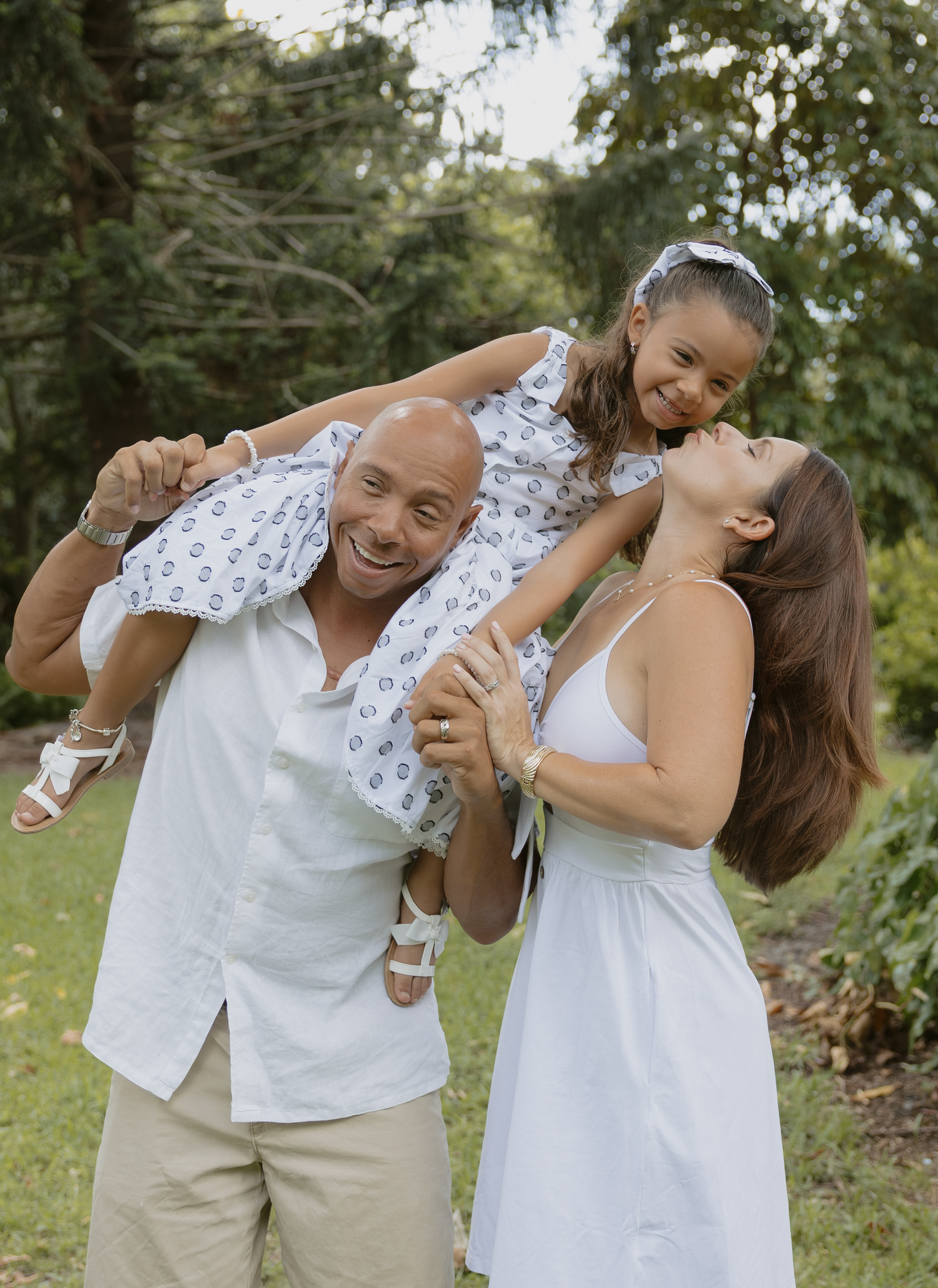 A couple shares joyful moments together in a series of playful poses outdoors in a natural garden setting.