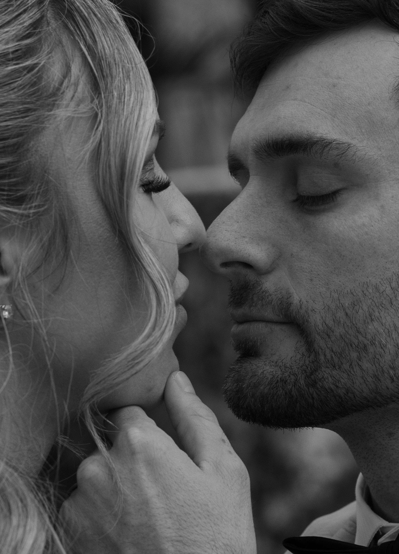 A romantic black and white close-up of a couple sharing an intimate moment with gentle touch and closed eyes.
