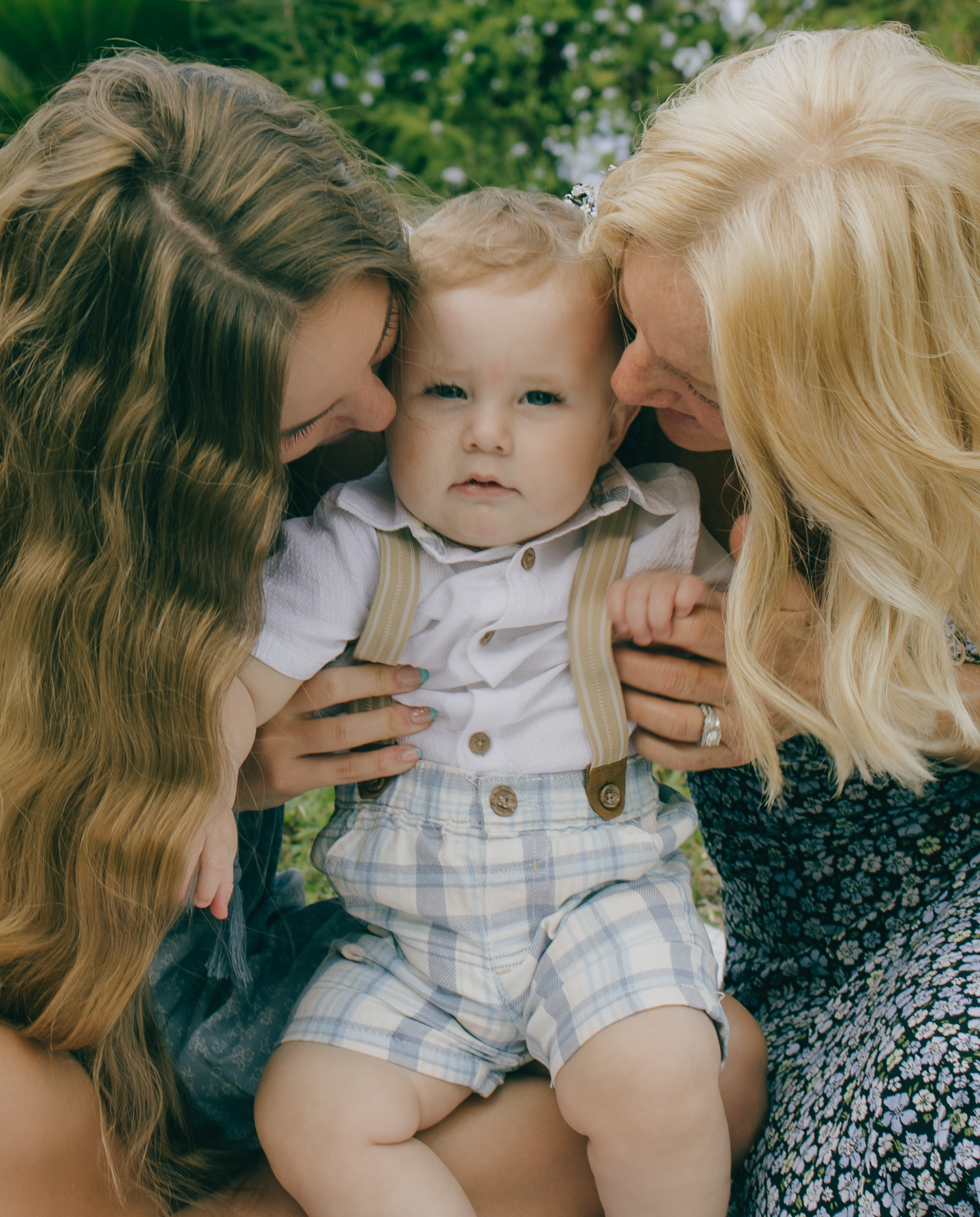 Loving family moment captured on blanket with baby in blue and white outfit.