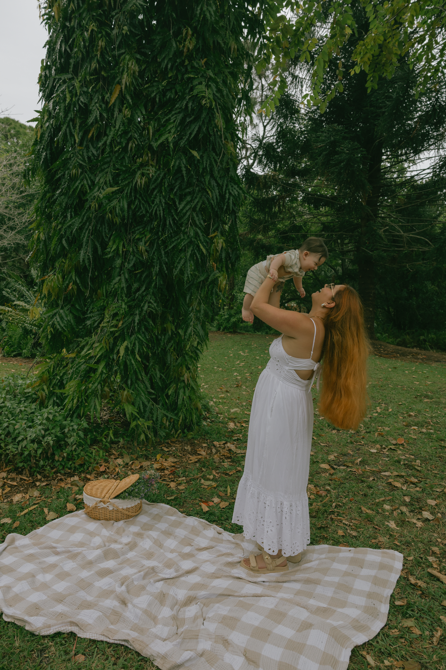 Parent lifting child in air during playful moment at outdoor picnic.