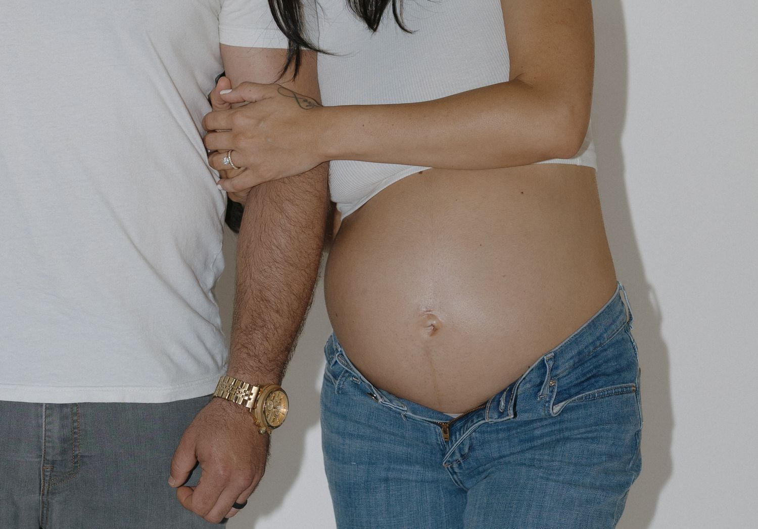 Close-up maternity shots highlighting pregnancy in casual denim and white ensemble.