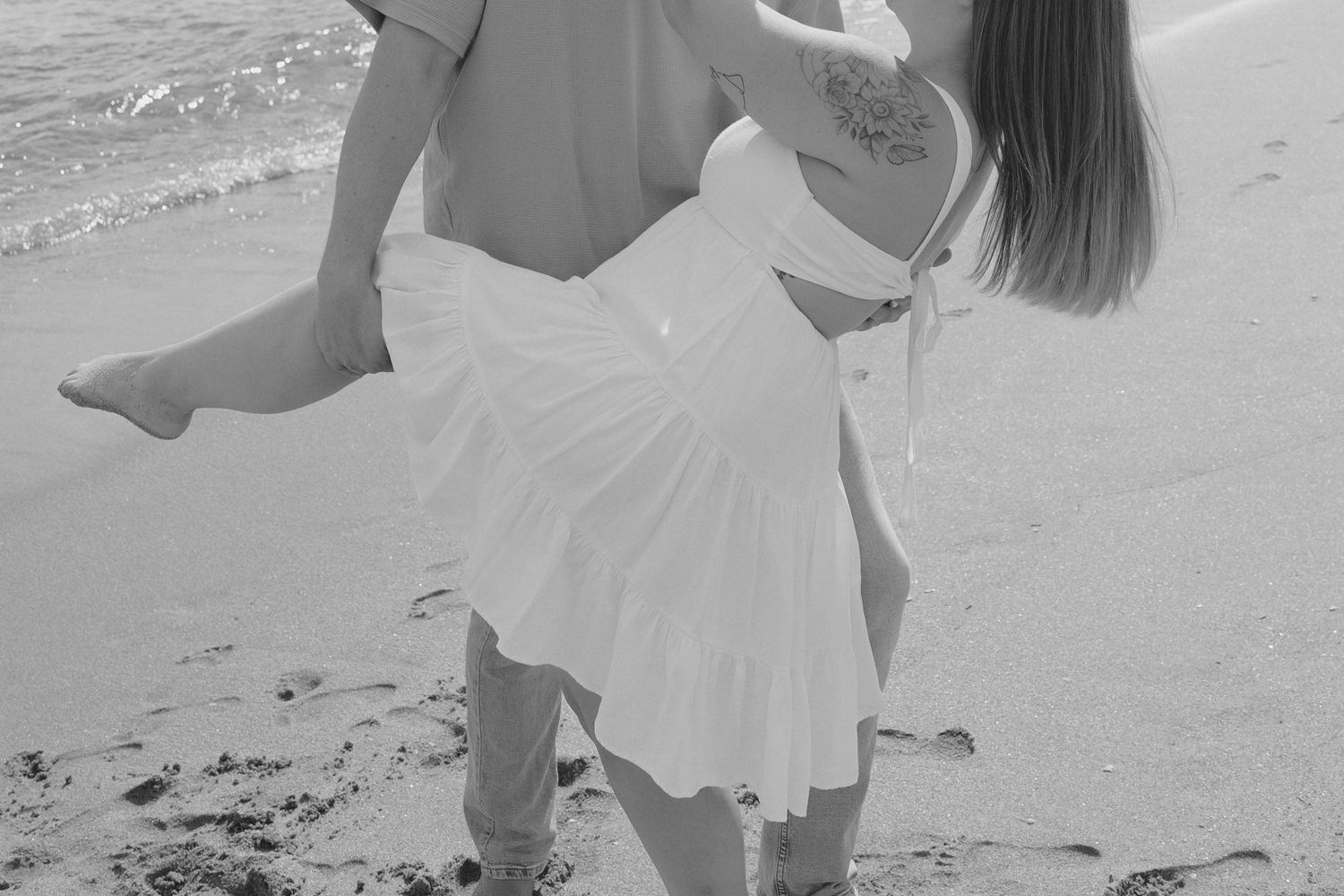 A series of black and white candid photos showing someone in a flowy white dress walking and twirling on a beach.