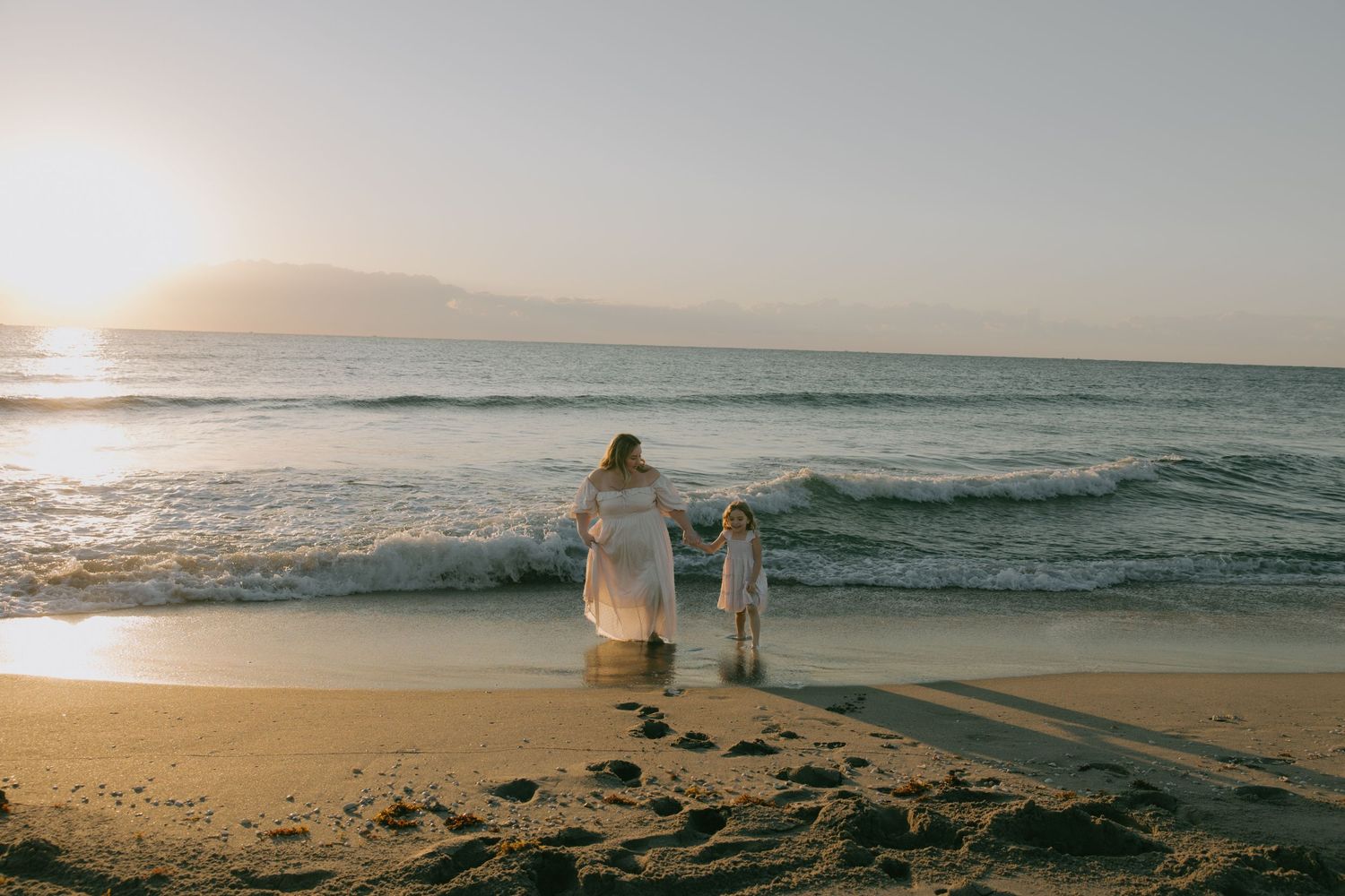 Wide shot of sunset beach with distant figures walking along the shoreline.