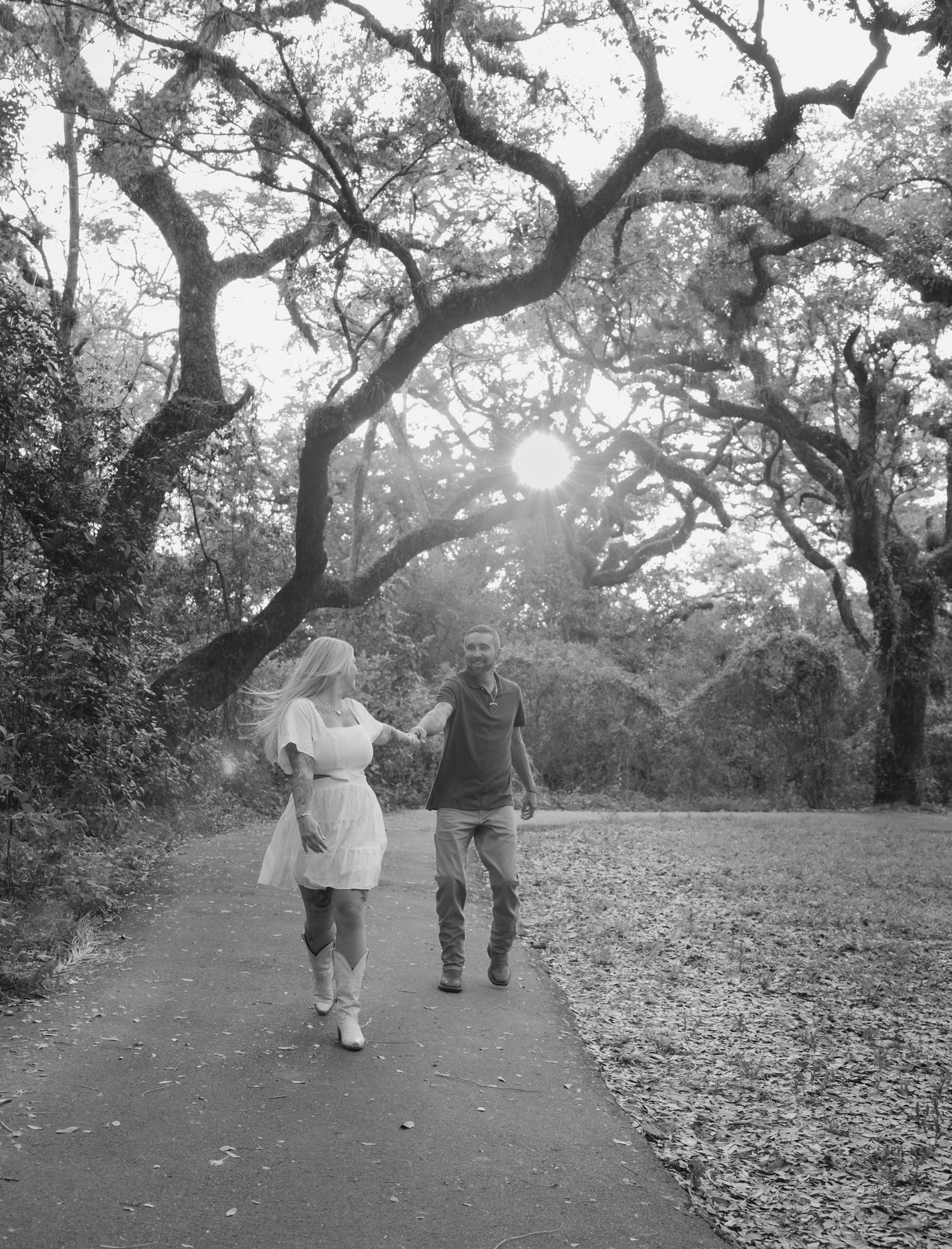 Black and white sequence of a couple walking and posing under majestic oak trees.