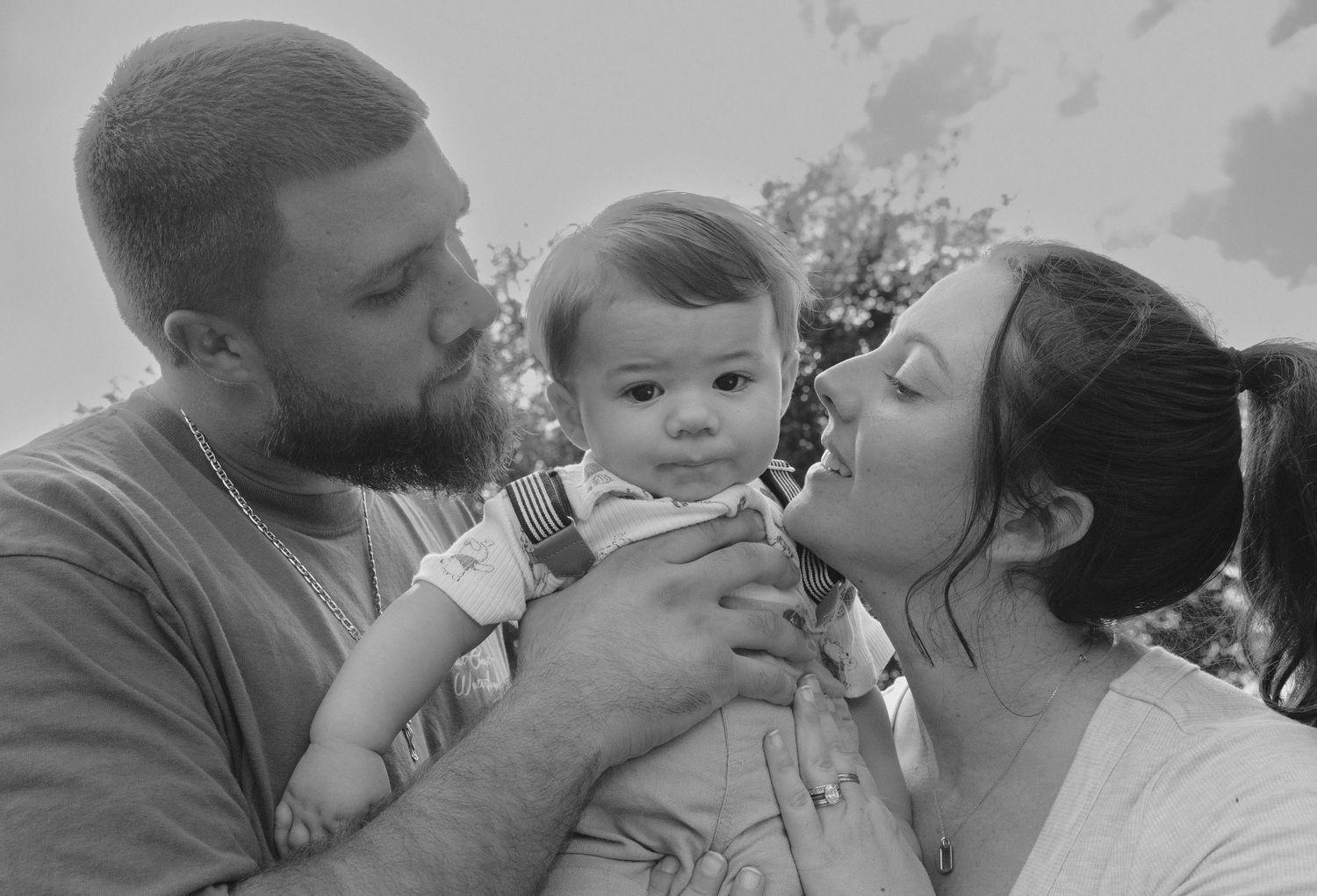 A series of five black and white photos showing tender family moments with a baby.