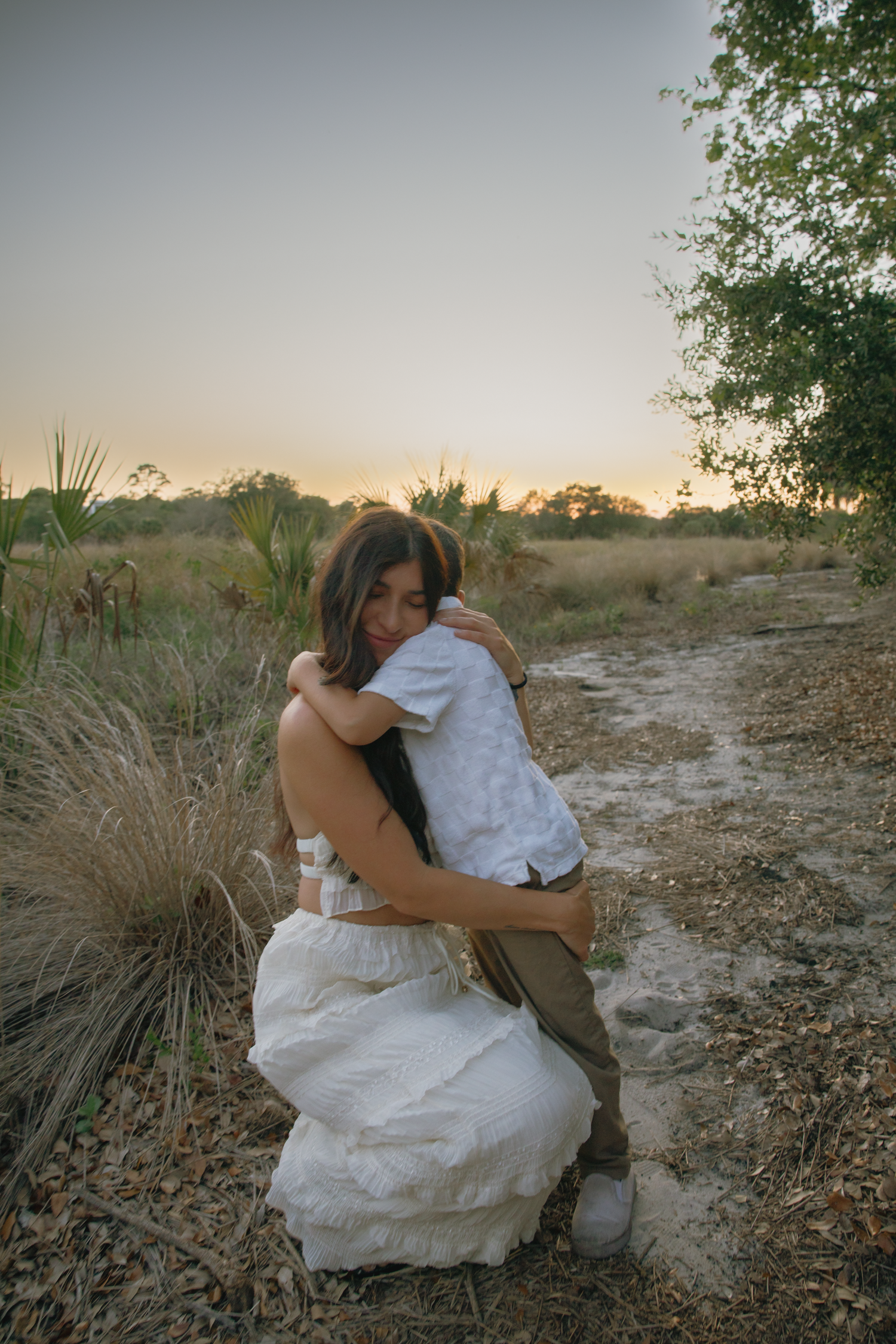 A tender moment captured between mother and child hugging on a nature trail at dusk.