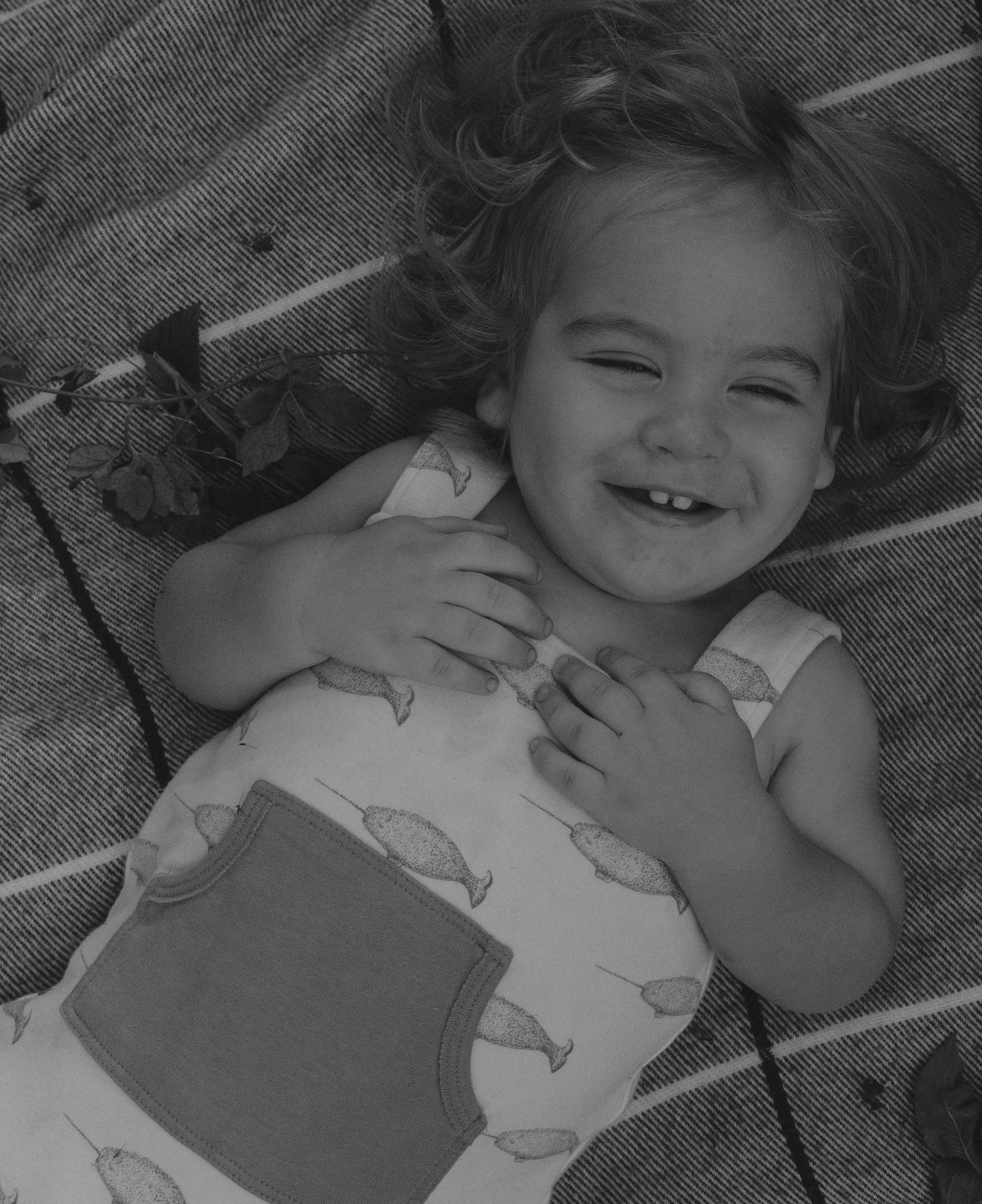 A series of black and white photos showing a child lying down and making playful expressions.