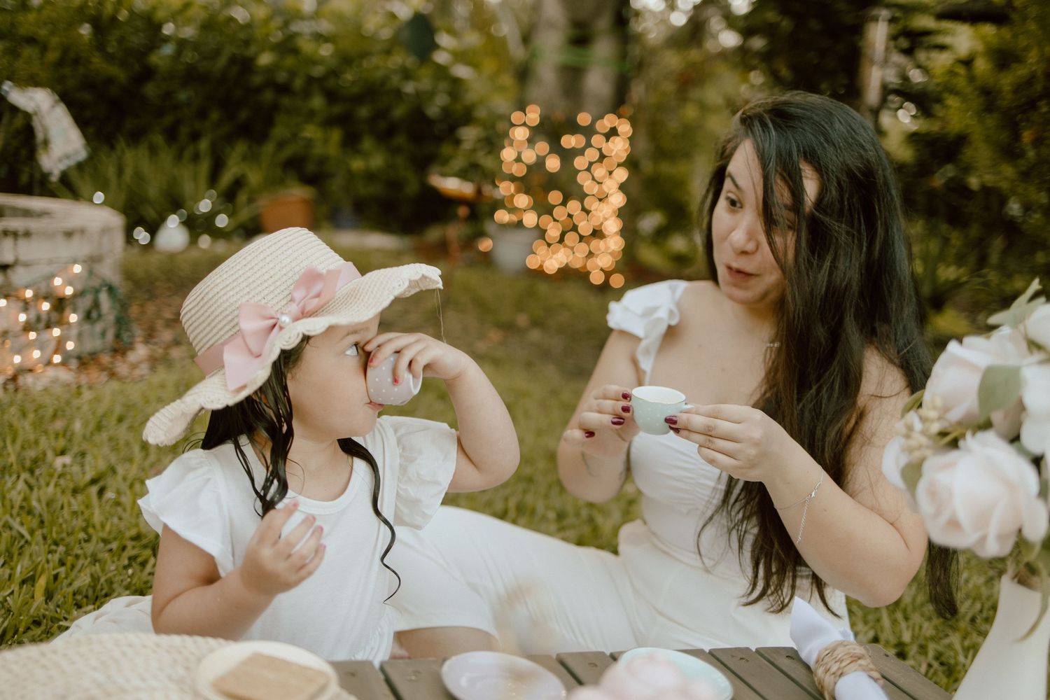 Sweet outdoor tea party moment captured with delicate teacups and pastel decor.