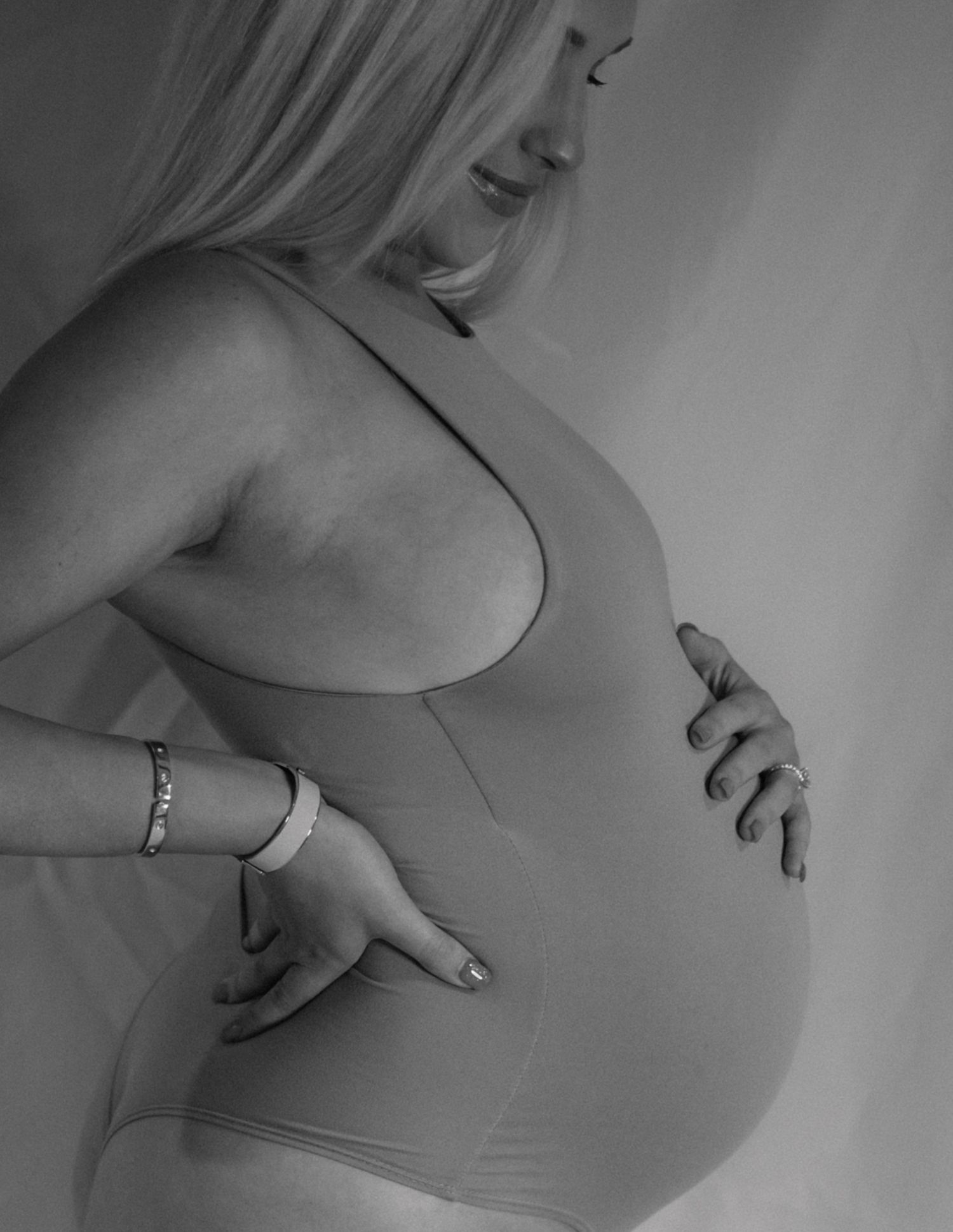 Intimate black and white portrait of pregnant belly with gentle hands.
