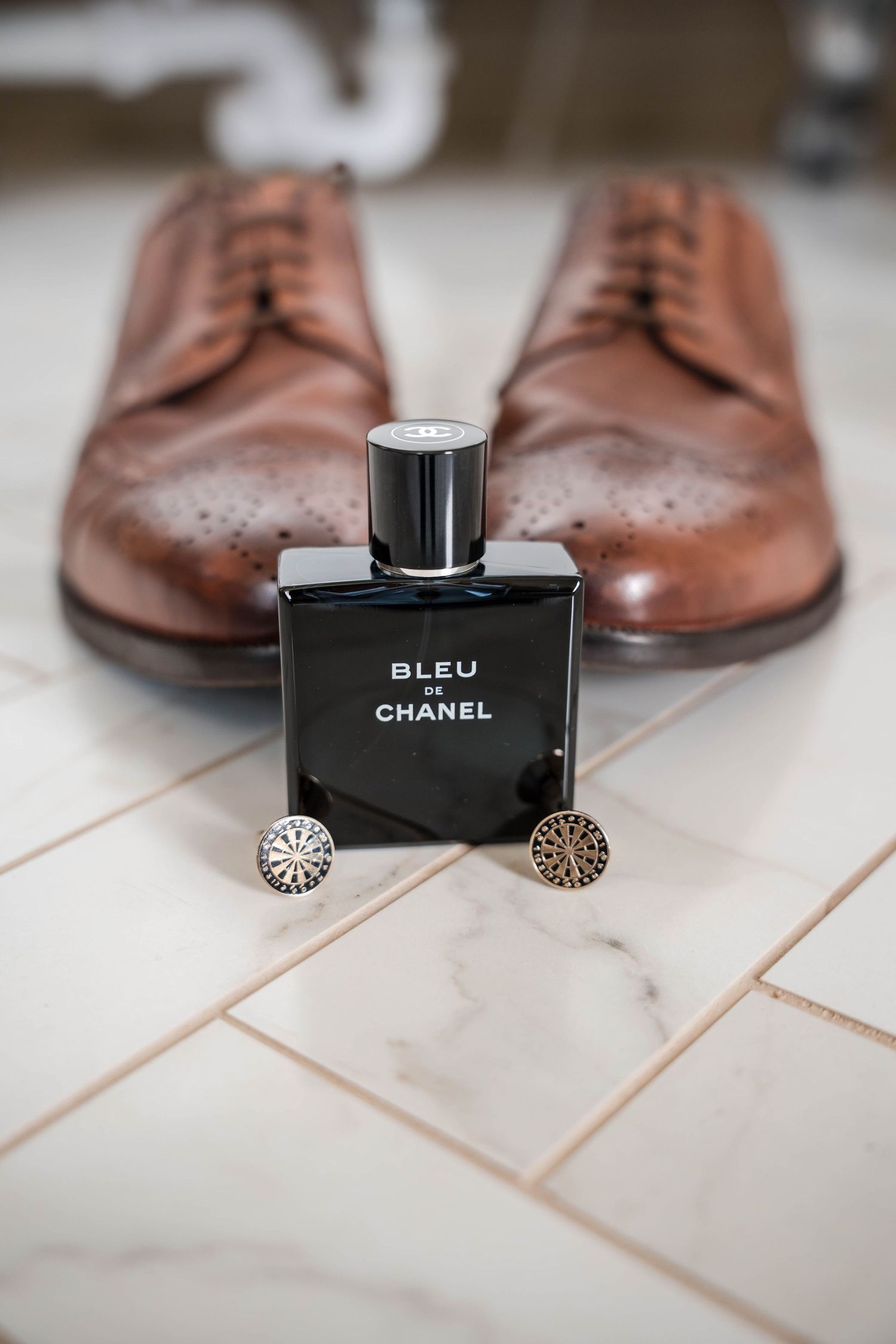 Brown leather dress shoes and Chanel fragrance bottle arranged on light tile surface.
Stockton house wedding venue