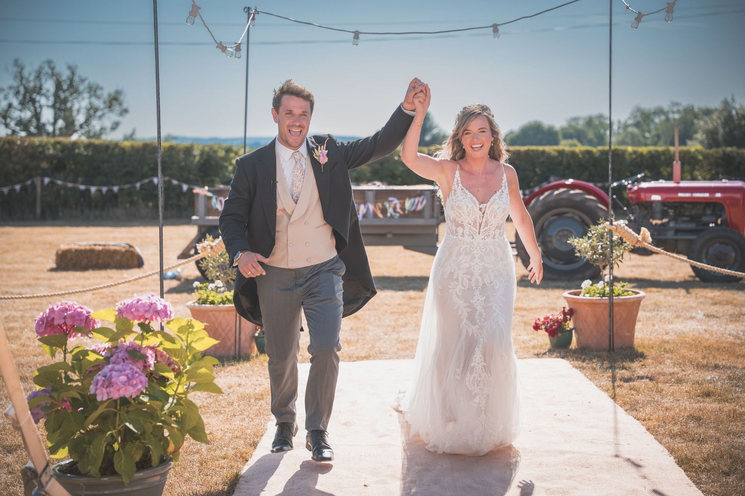 A happy couple celebrates their outdoor wedding festivities while walking in the sunlight.