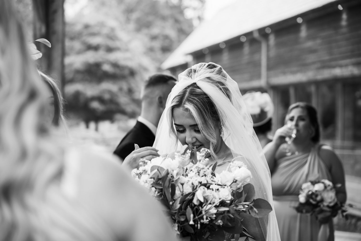 A joyful bride holding a white bouquet laughs during an outdoor wedding celebration.
The Mill Barns wedding venue