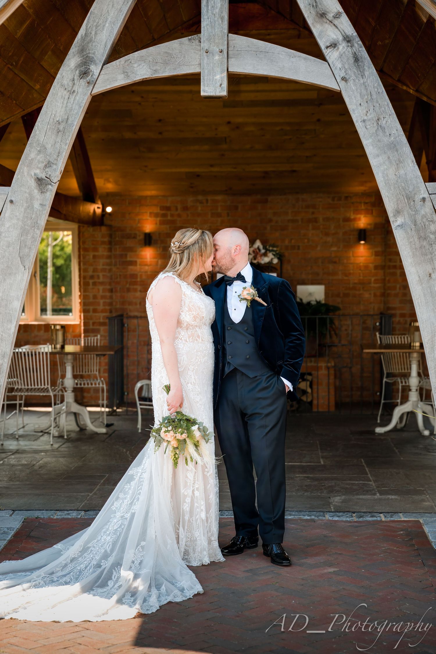 Wedding couple shares intimate moments under rustic wooden arches.