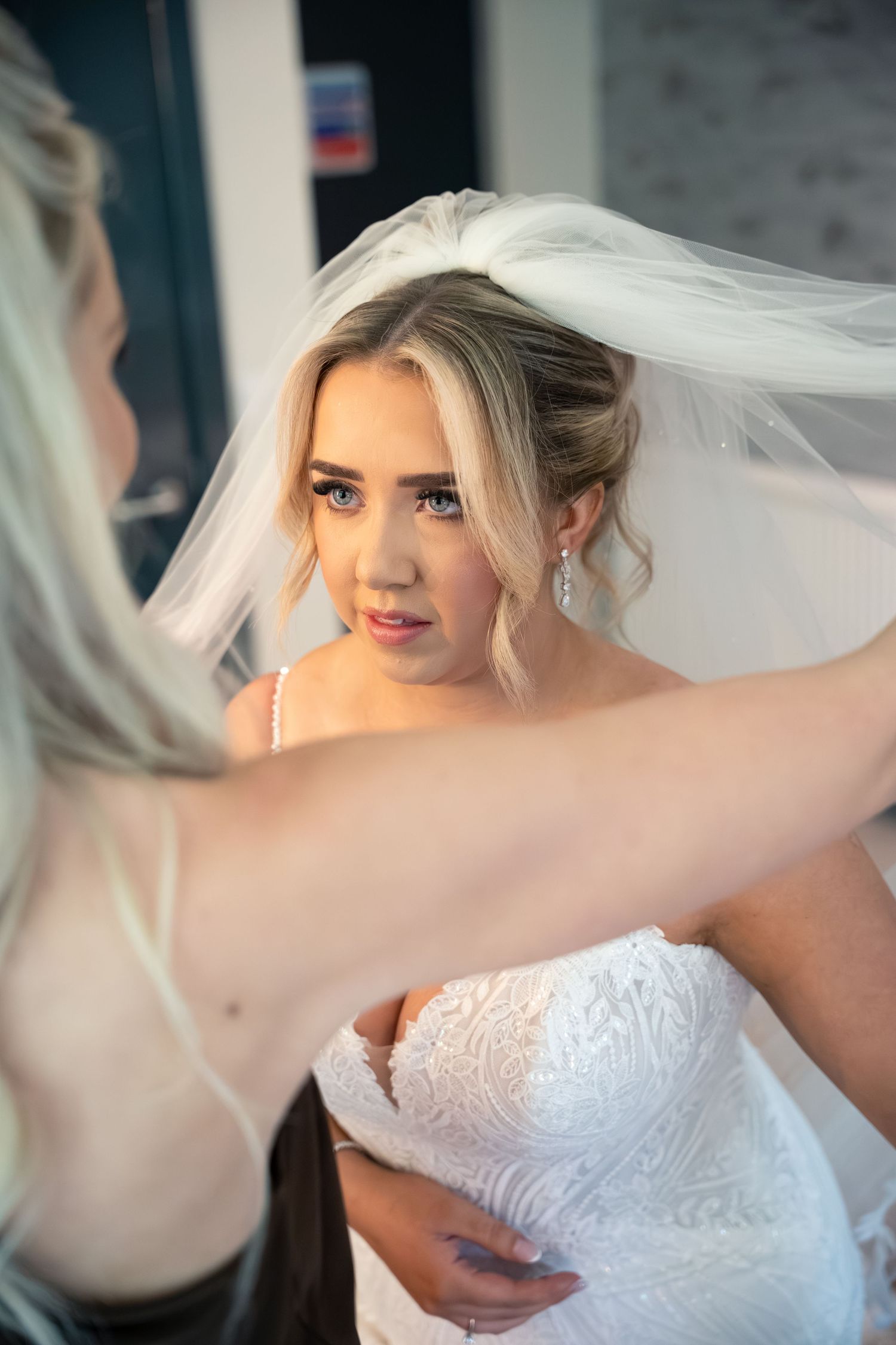 A bride in a white lace gown and veil gets final adjustments to her wedding day look.
The Mill Barns wedding venue