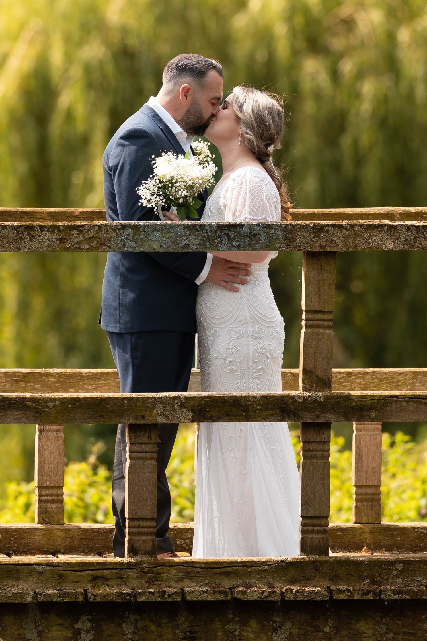 Romantic moment captured on rustic wooden bridge with willow trees in background.
Malvern hills council house wedding venue