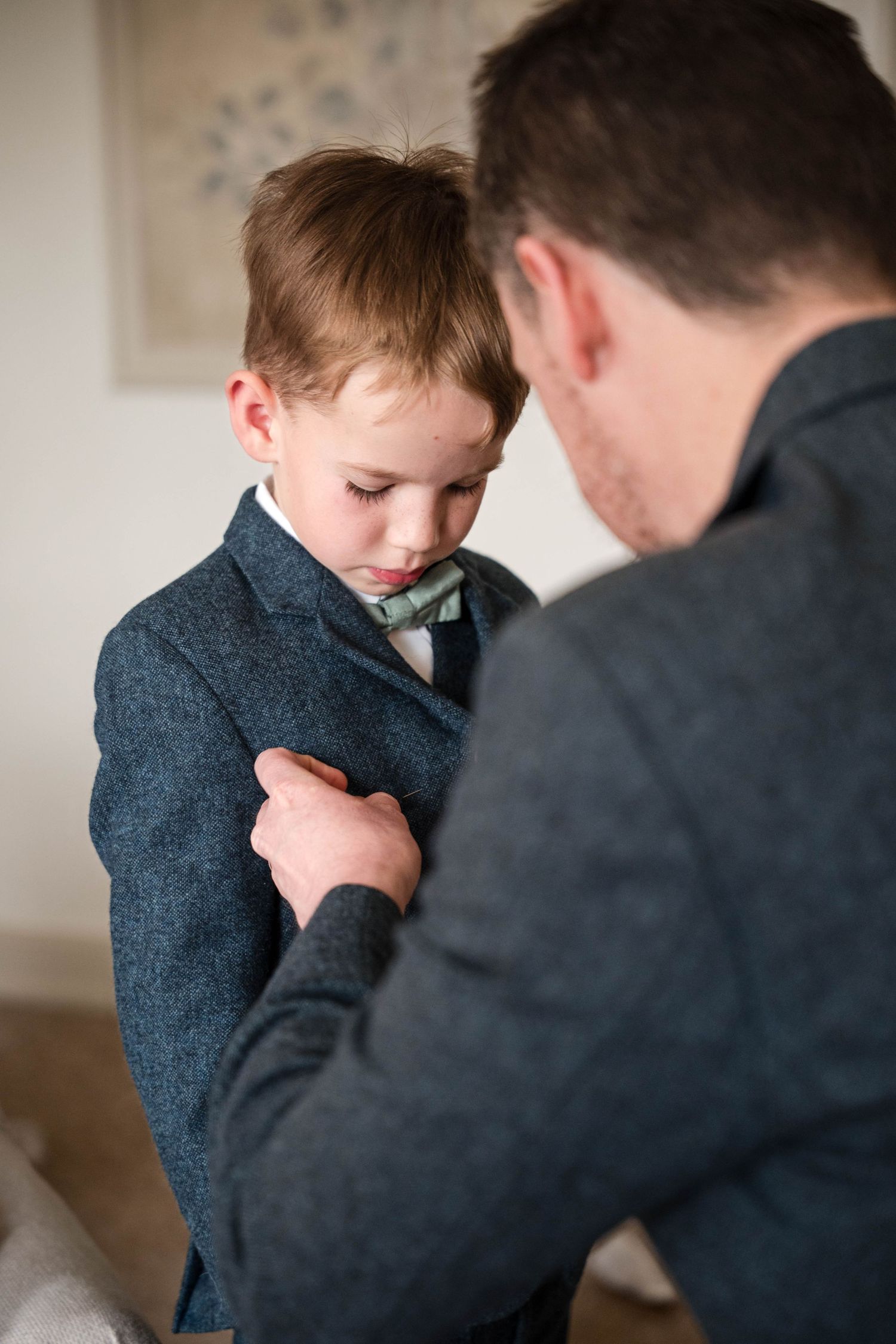 Father and young son sharing intimate moment while adjusting formal attire.
