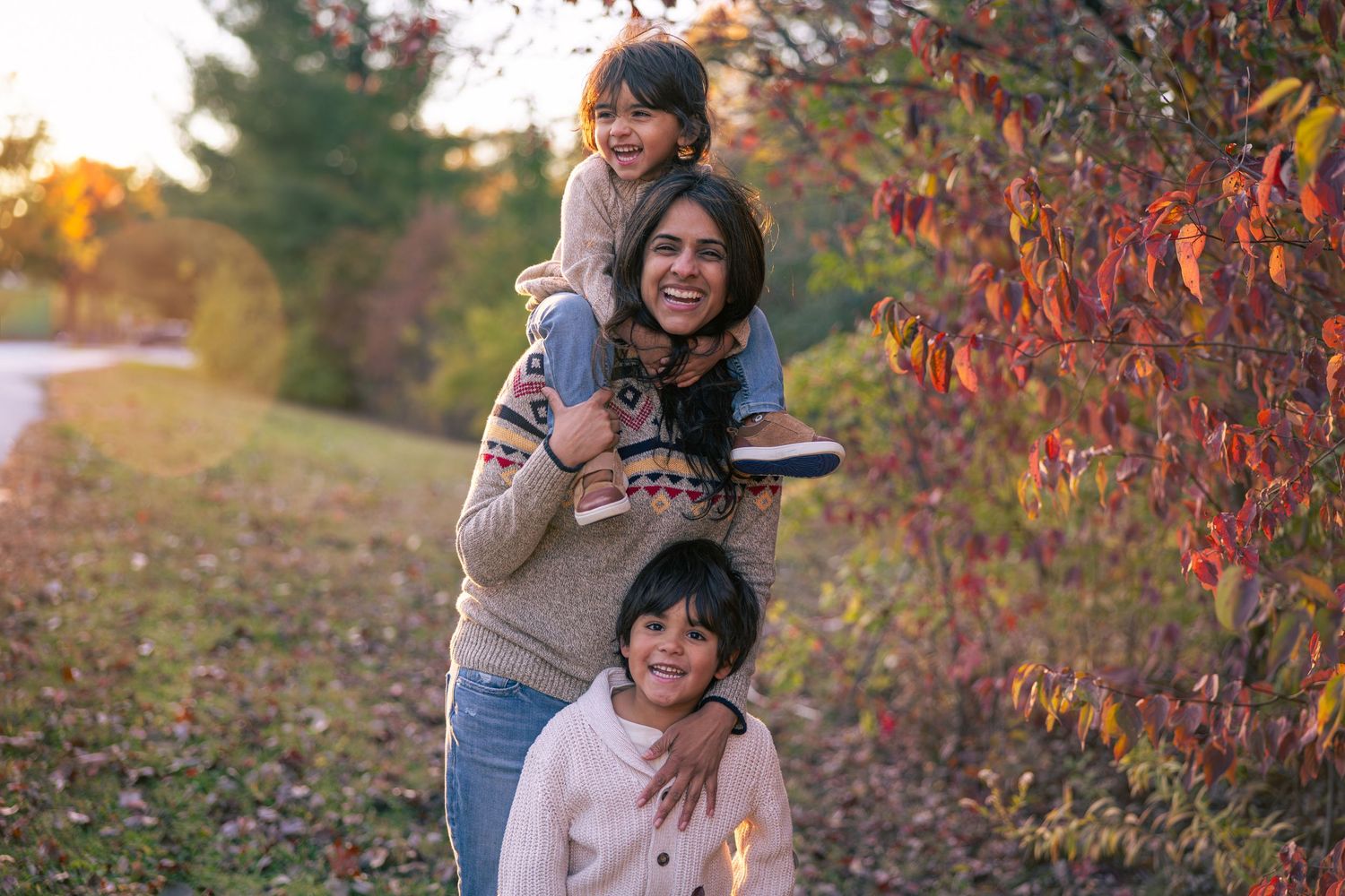 A joyful outdoor autumn portrait with colorful fall foliage in the background.