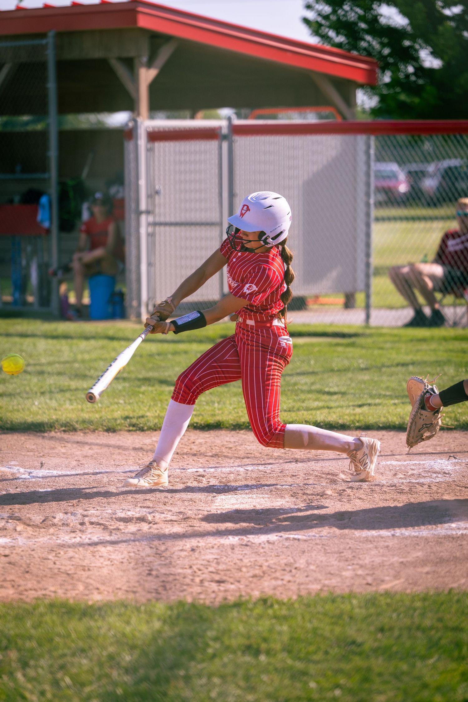 Baseball player sliding into base during game showing red striped uniform pants.
