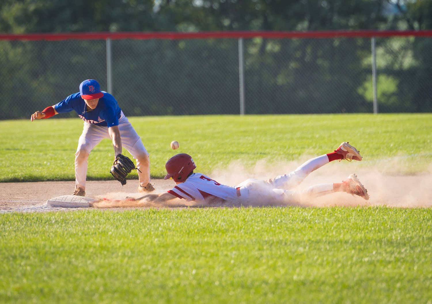 Baseball players in action on sunny field during competitive game.