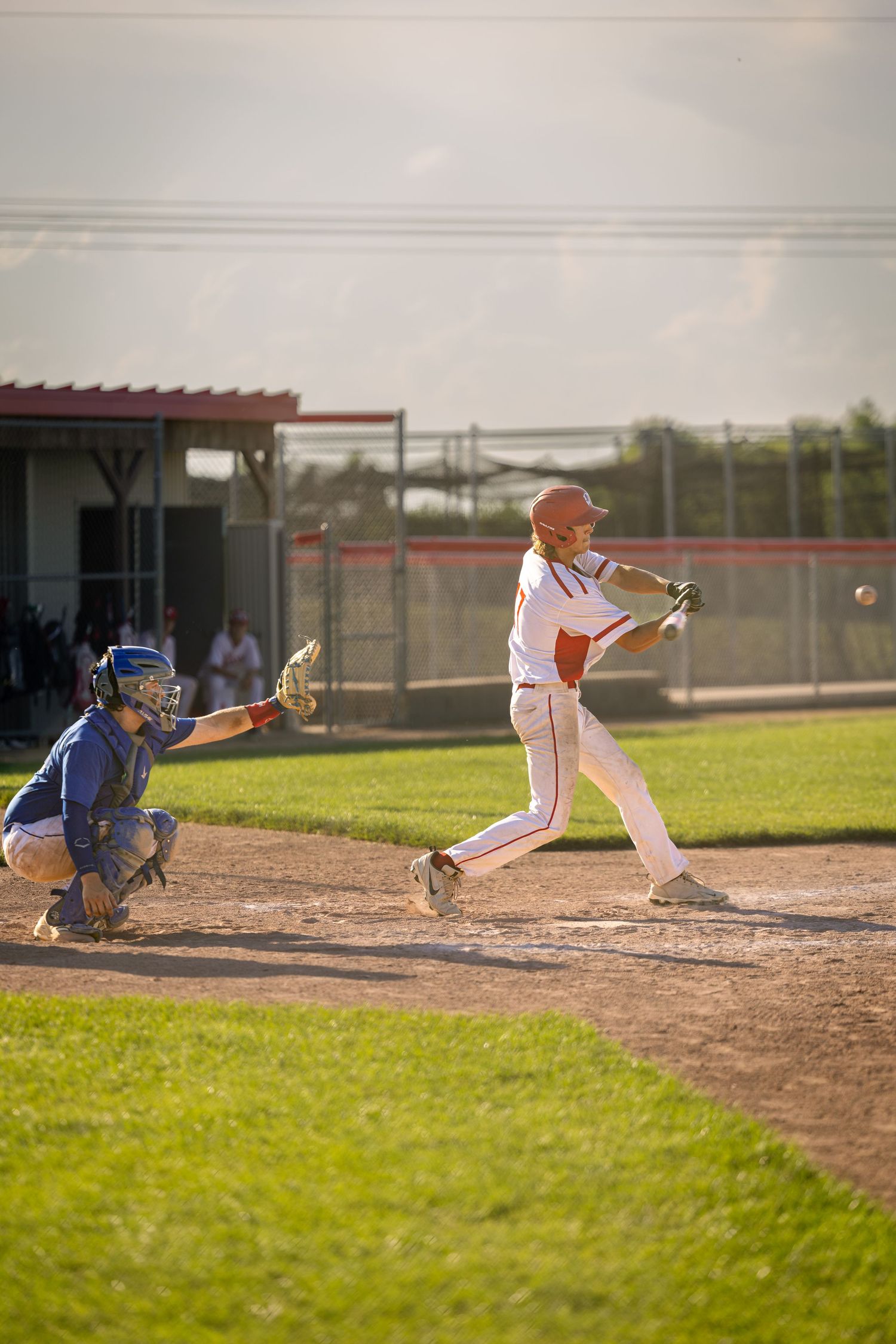 Baseball batter swinging at pitch during game with catcher and umpire.