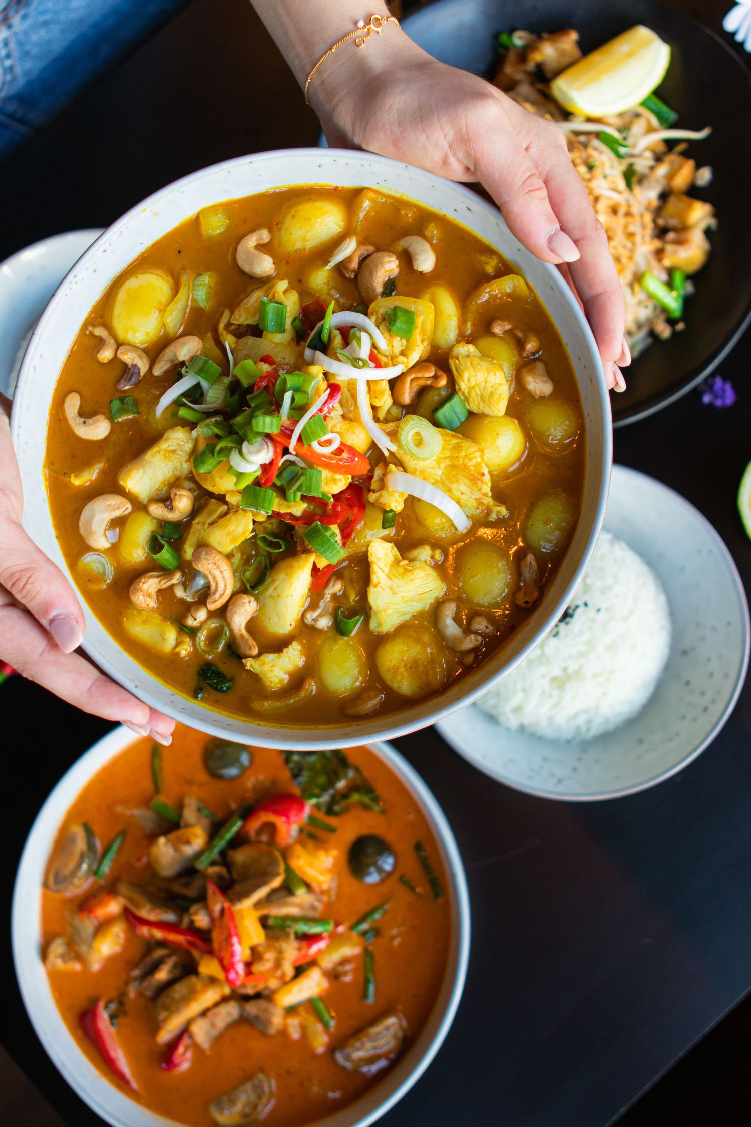 Two bowls of colorful curry soups garnished with fresh herbs and vegetables.