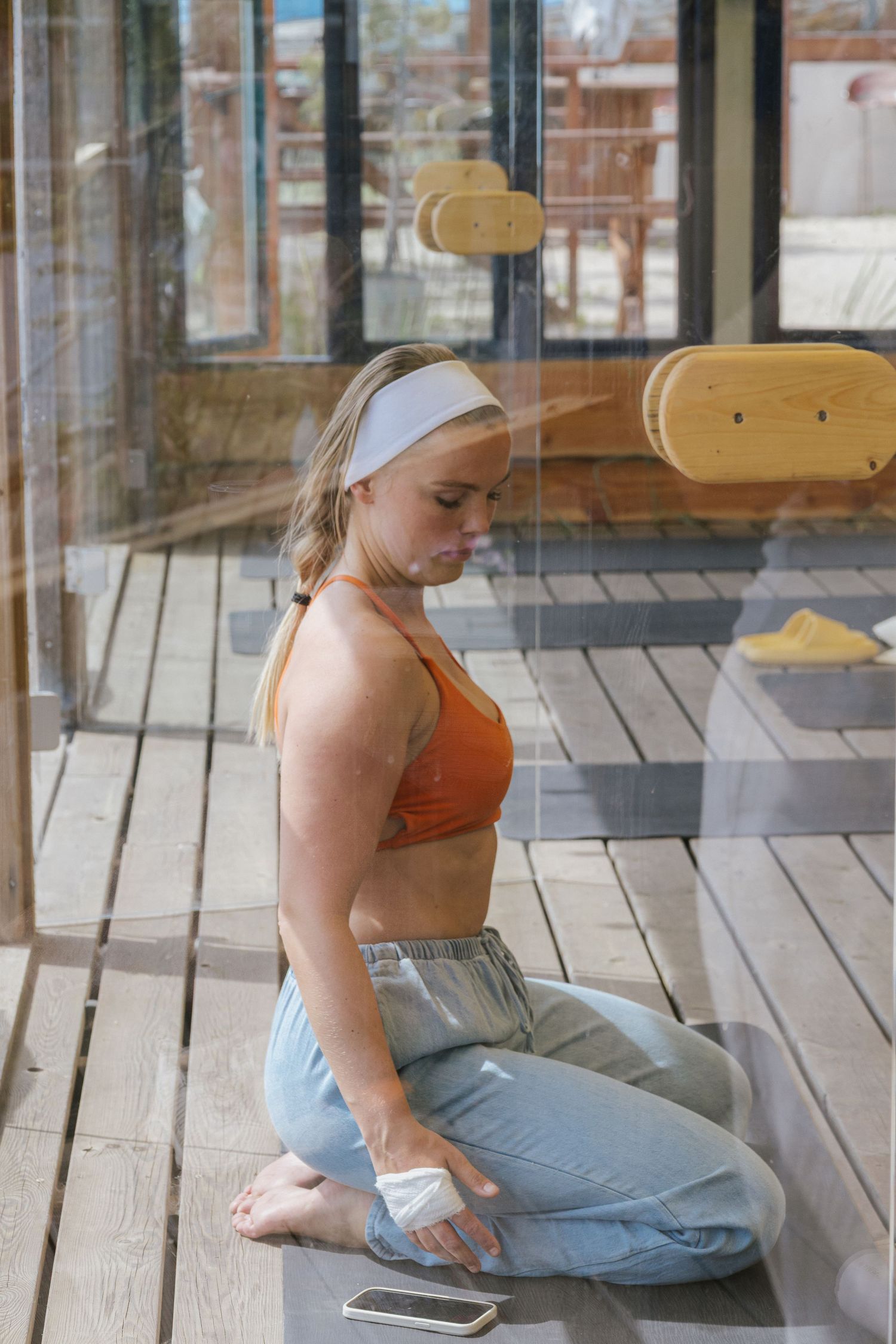 Person in casual attire sitting on wooden deck in relaxed pose.