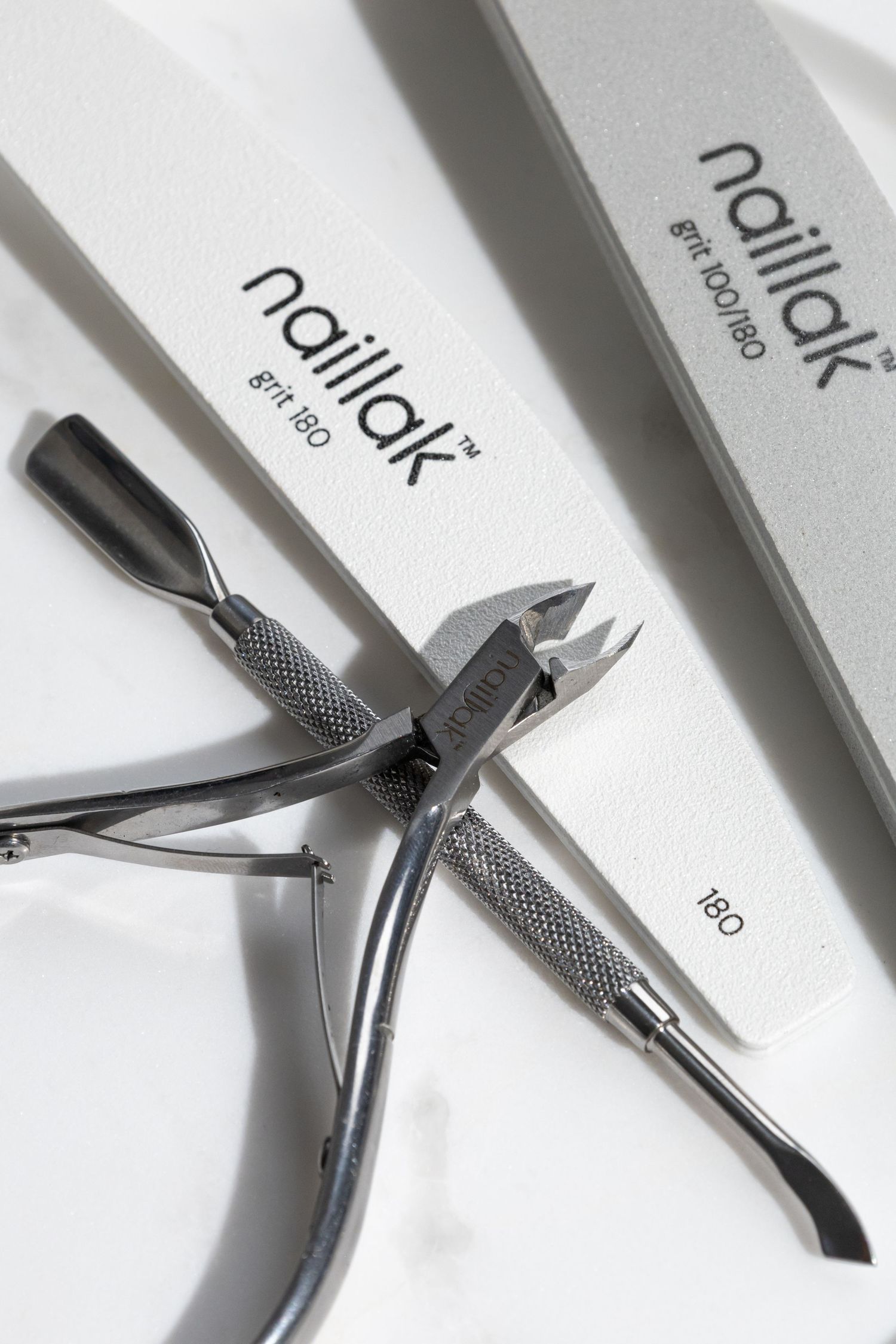 Naillak brand nail tools including cuticle nippers and nail files with 180 grit on white background.