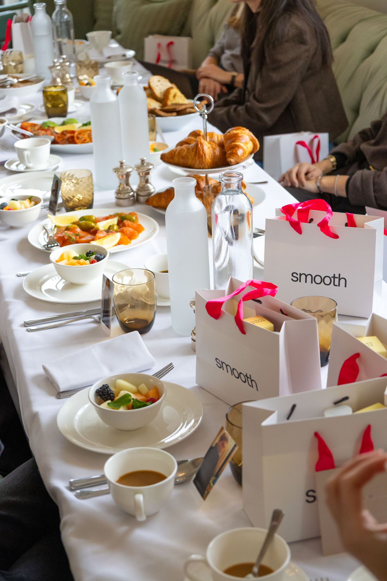 Elegant restaurant table setting with white linens, pink accents, and various plated dishes for a formal dining experience.