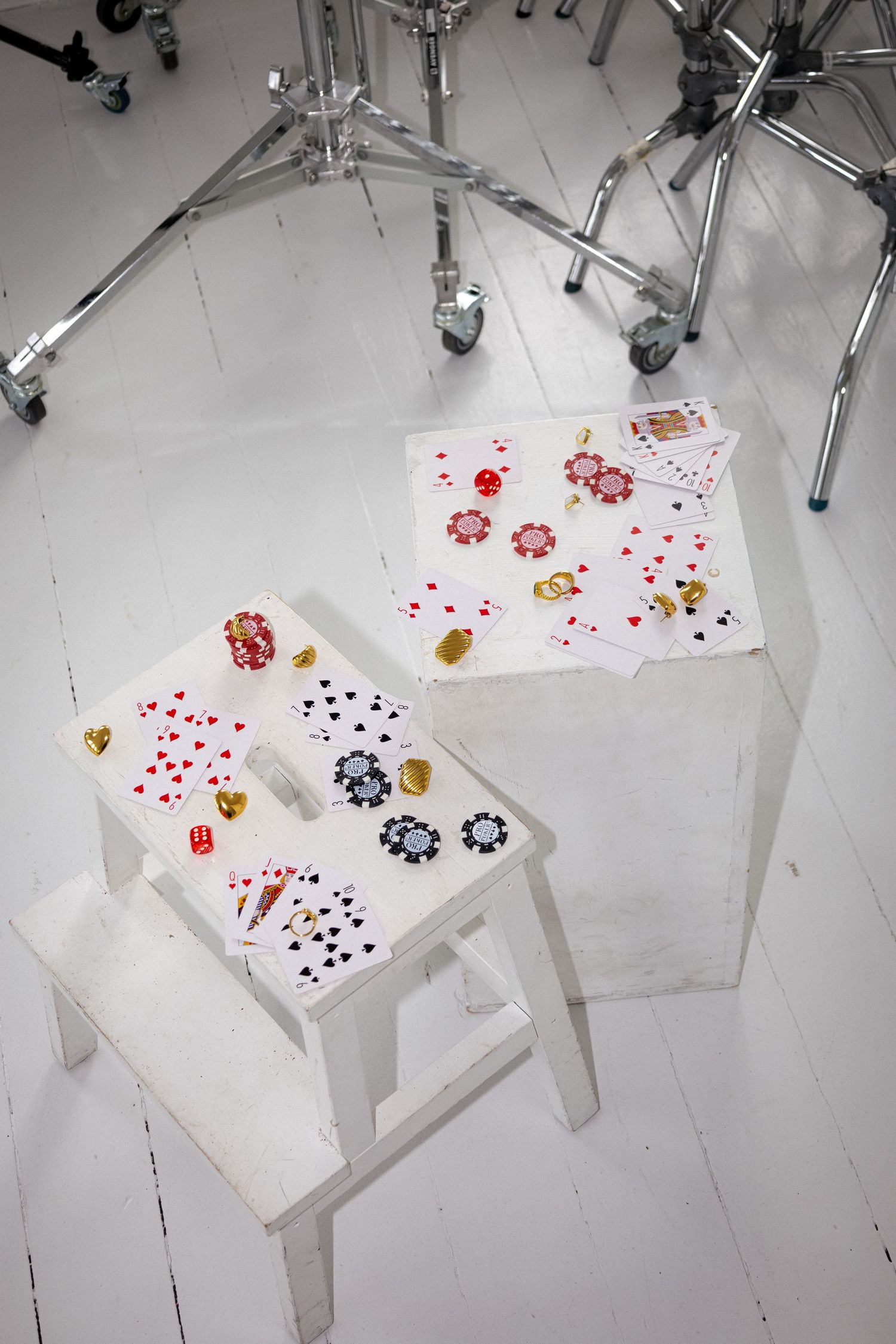 Overhead view of playing cards and poker chips scattered on a white surface.