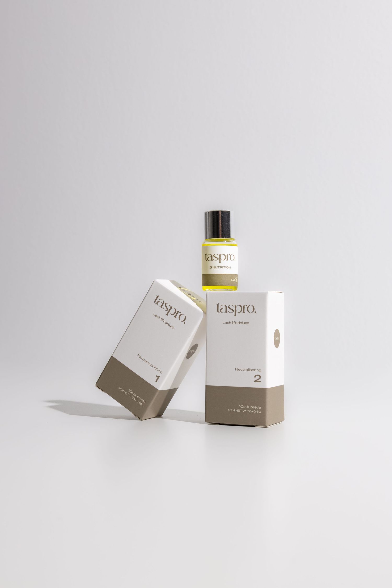 Two Taspro skincare boxes with a yellow serum bottle on a white background, minimalist packaging design.
