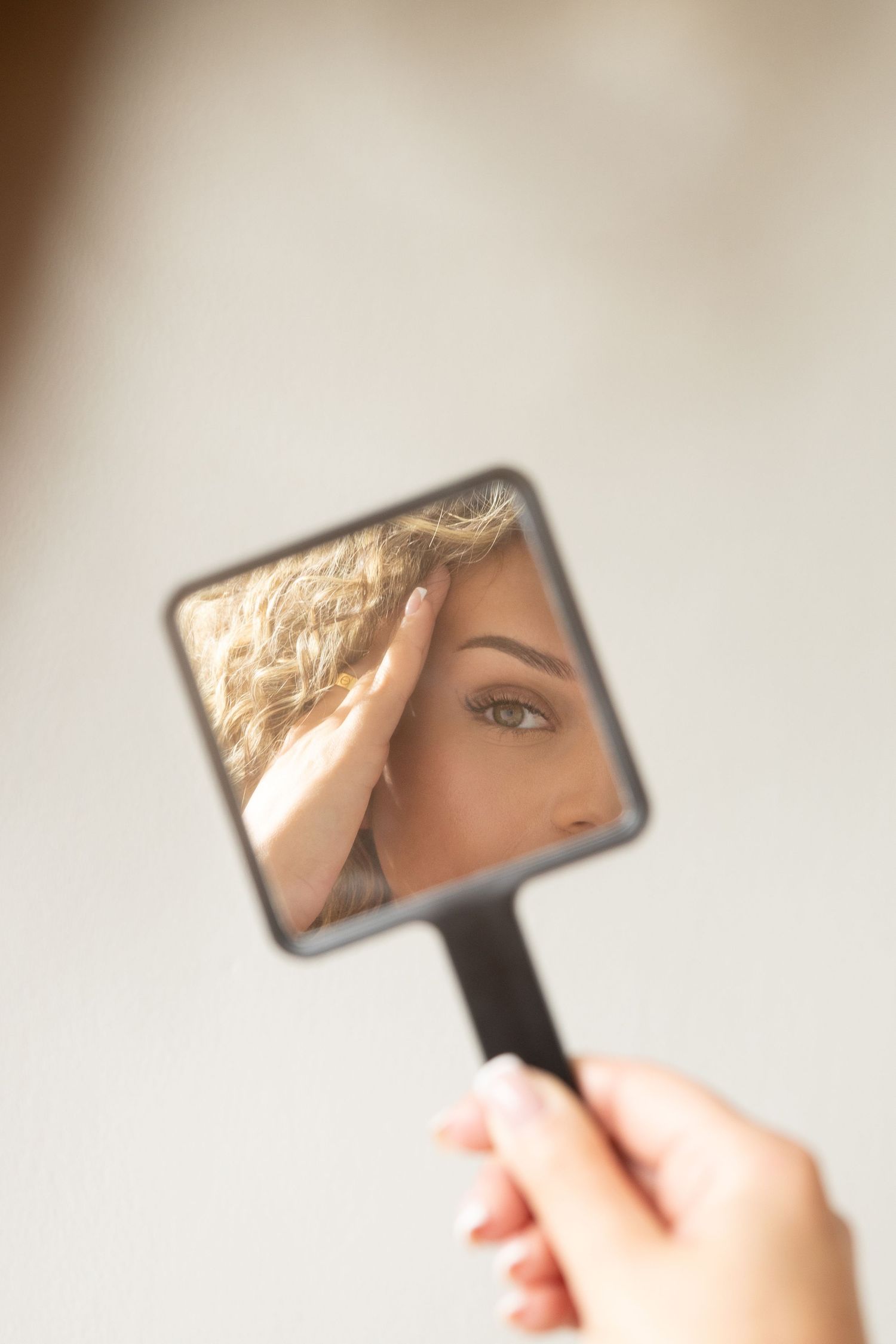 Small rectangular mirror reflecting in natural light against neutral background.