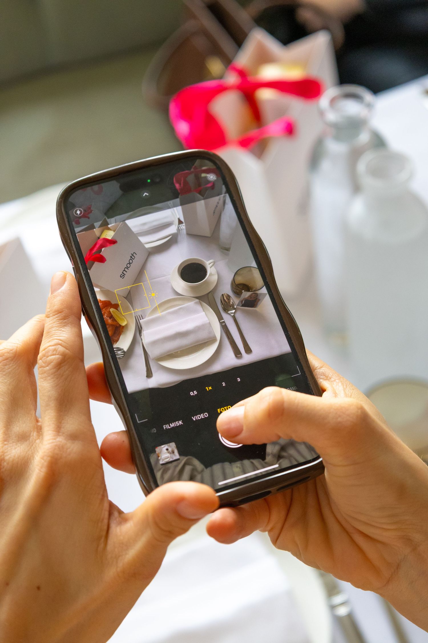 Multiple hands holding smartphones to take photos of a table setting.