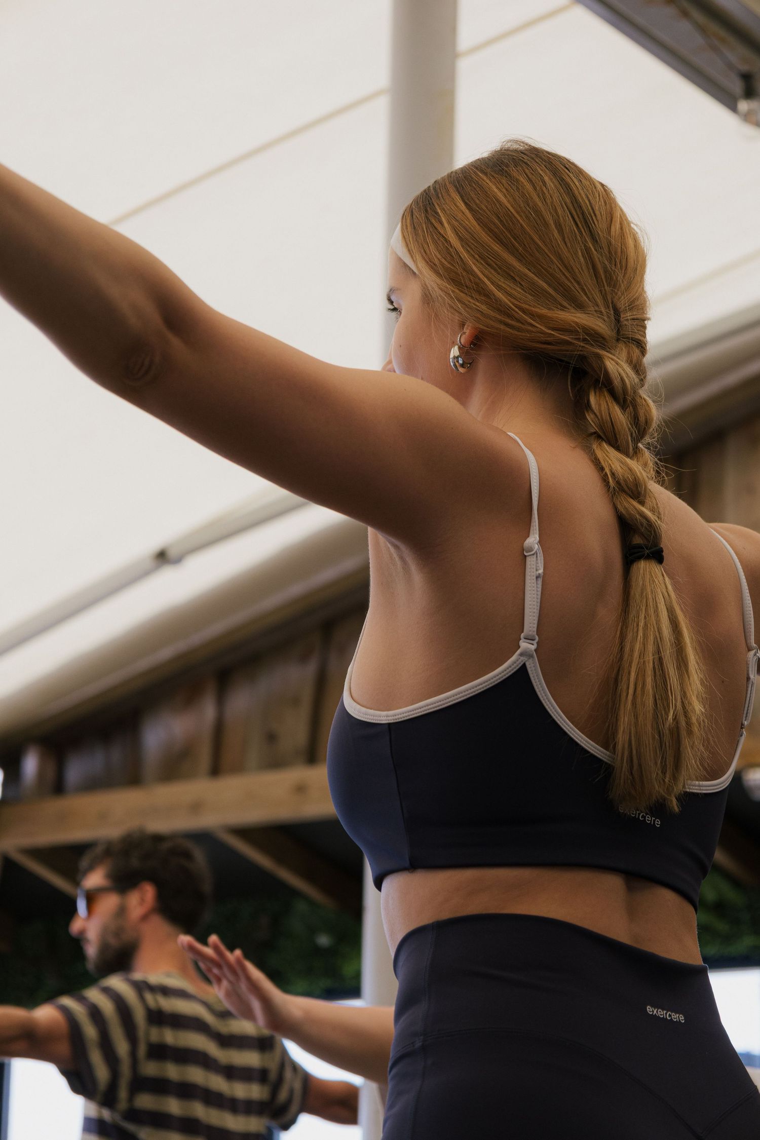 Group of people stretching with arms raised during fitness class.