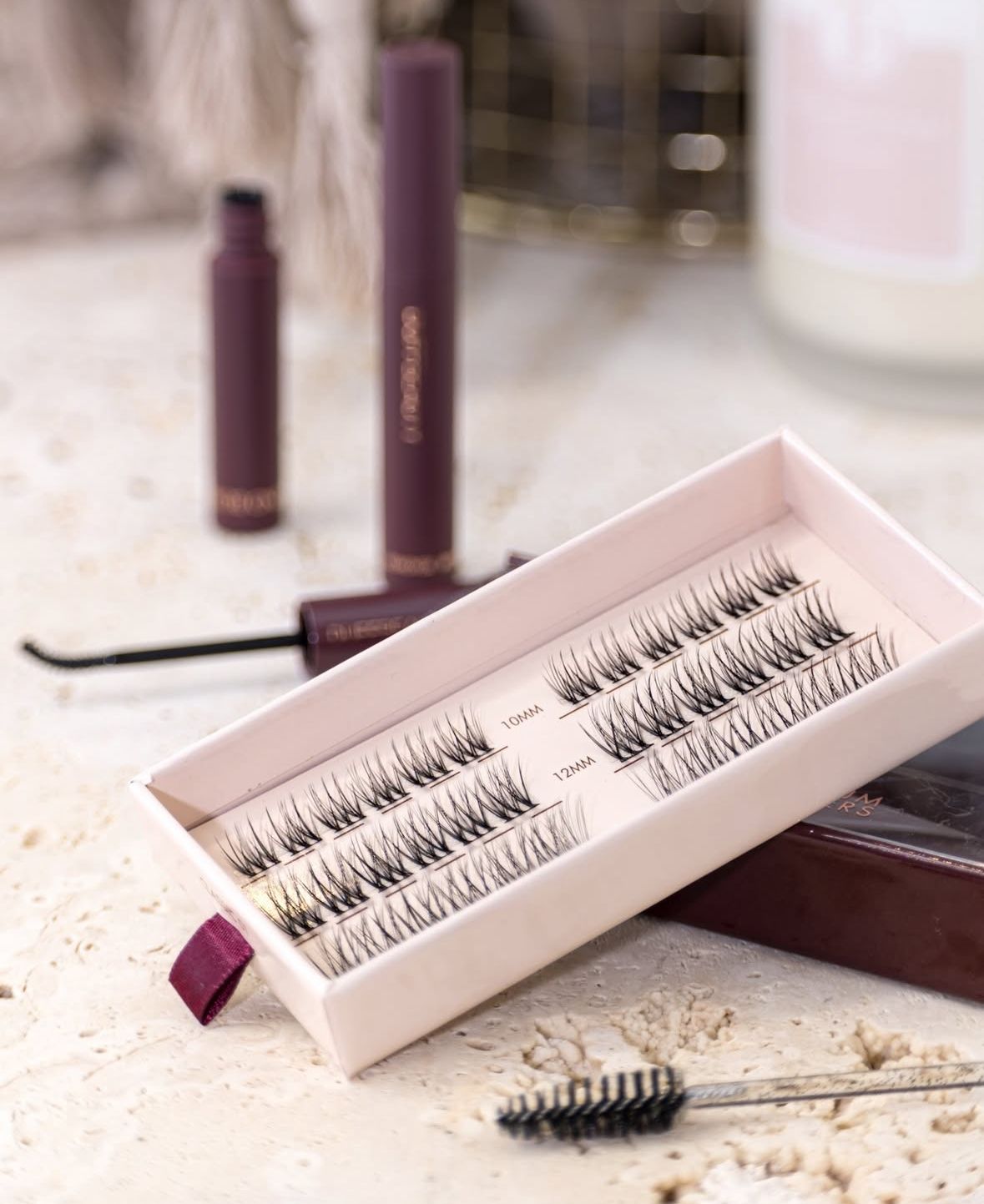 Close-up of false eyelash strips in pink packaging with applicator brush.