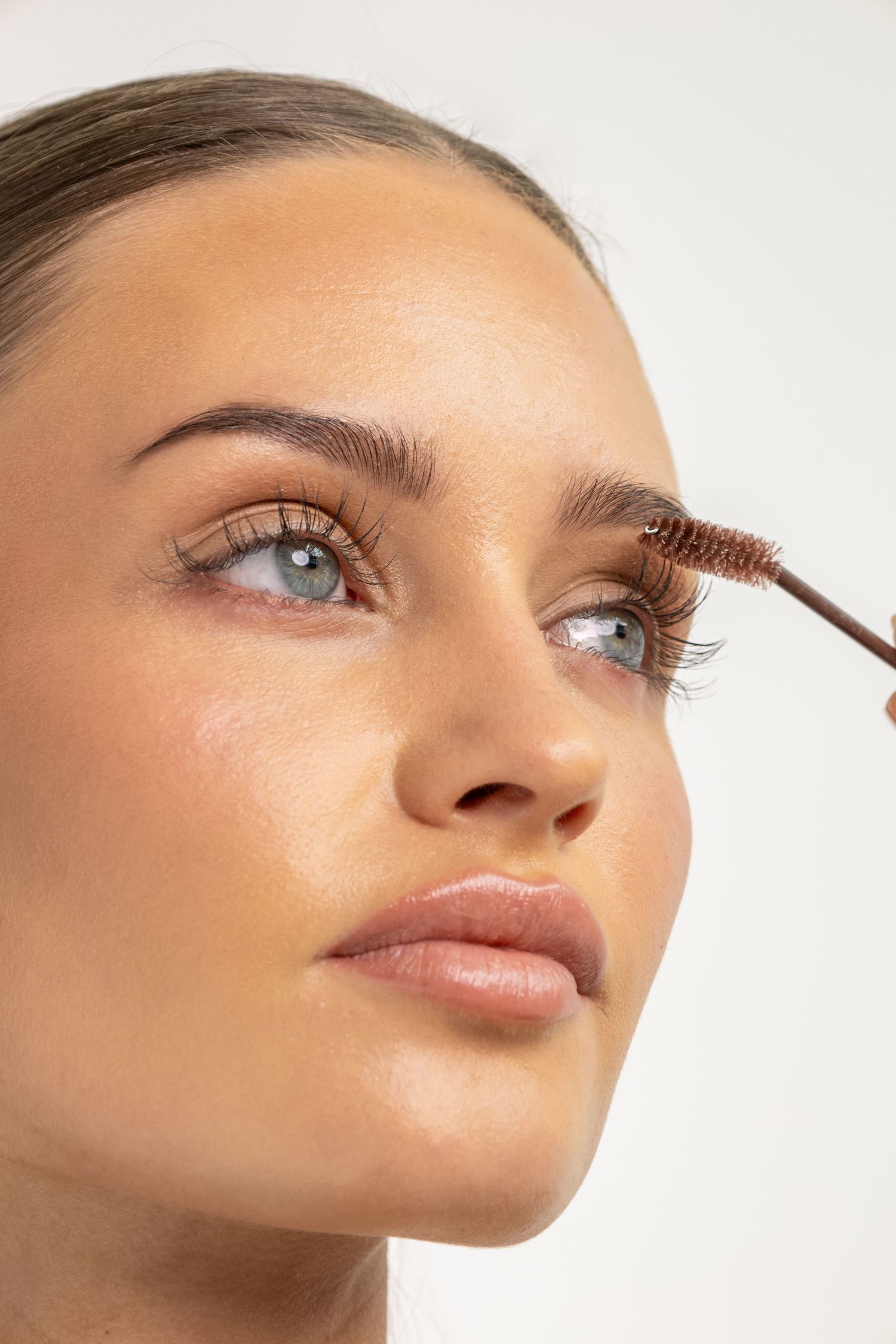 Close-up shot showing application of mascara to eyelashes against light background.
